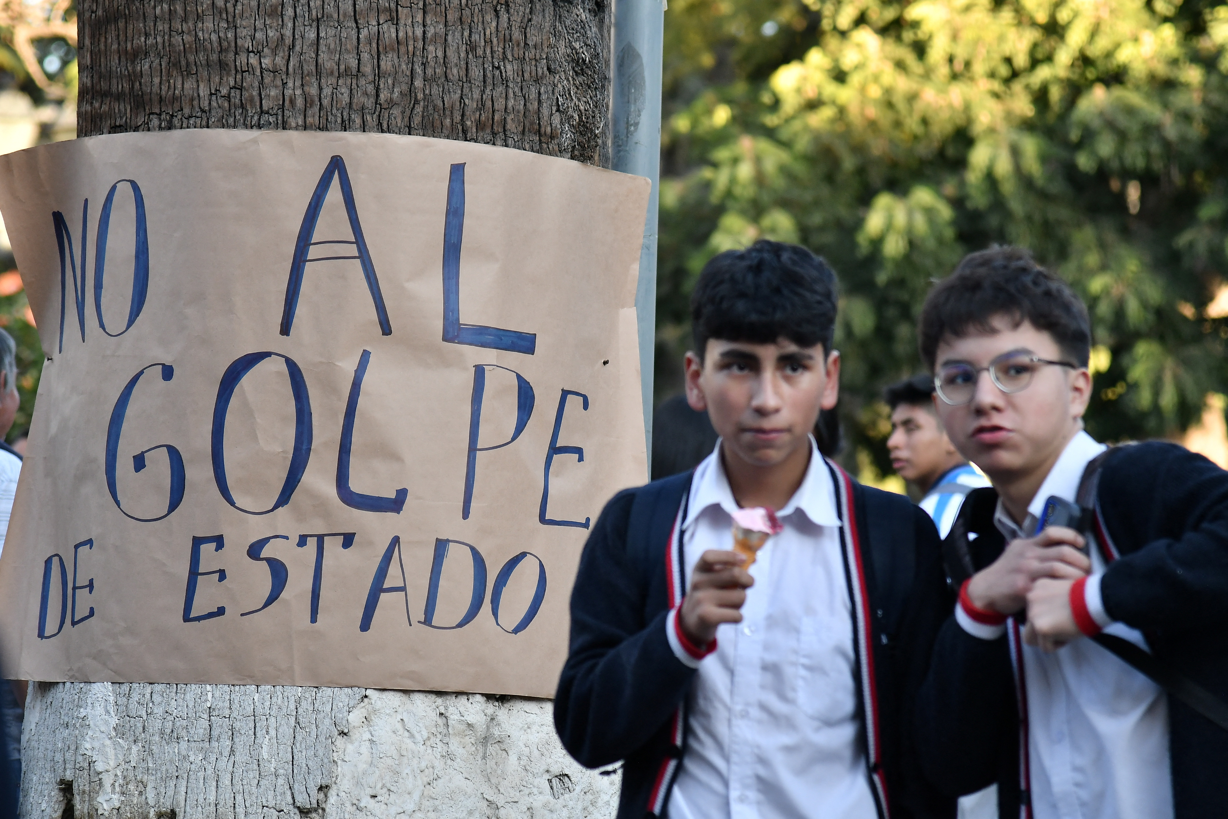 Kids eat ice cream in front of a hand-written sign denouncing the coup in Bolivia.