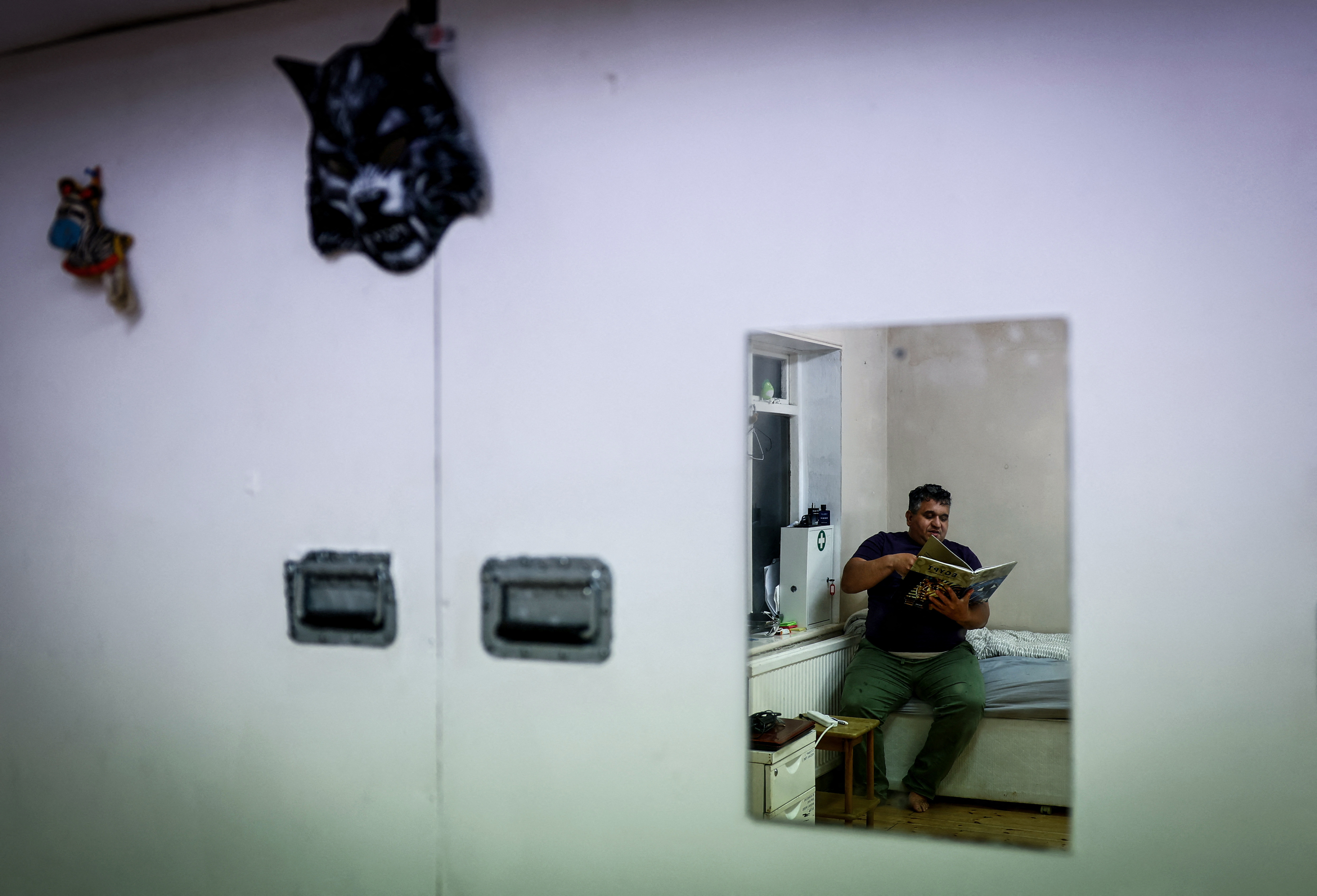 Youness Elaissaoui, 49, reads a book as he sits on his bed in the place he shares with other squatters, which was once a school and is now occupied by squatter activist group Reclaim Croydon, in Croydon, south London, Britain, May 17,