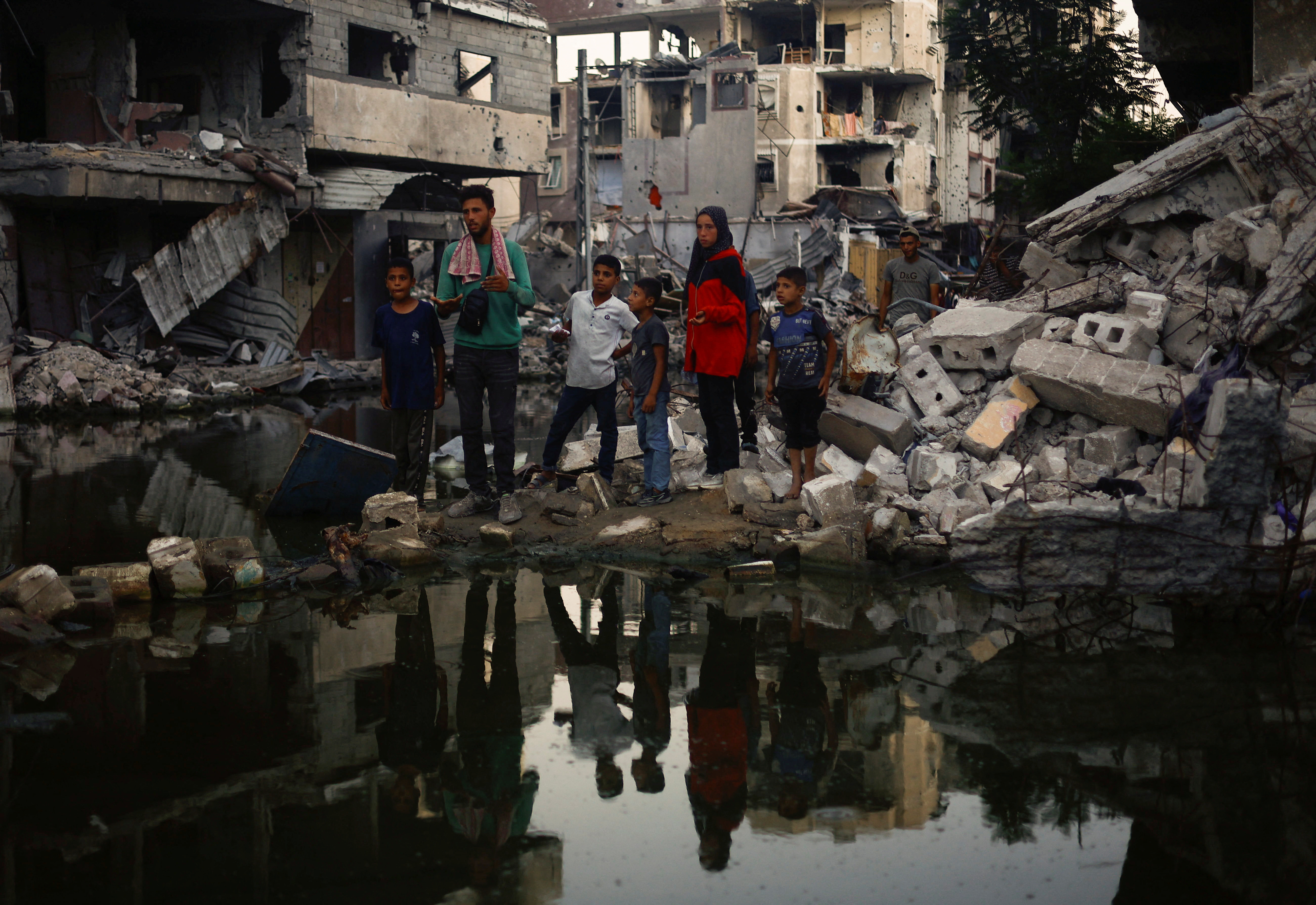 People stand near buildings destroyed in an Israeli strike, amid the ongoing conflict between Israel and Hamas, in Khan Younis, in the southern Gaza Strip, June 30, 2024. REUTERS/Mohammed Salem