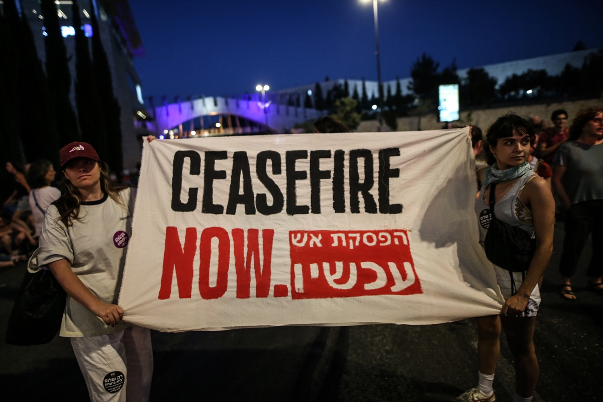 people hold a banner that says ceasefire now