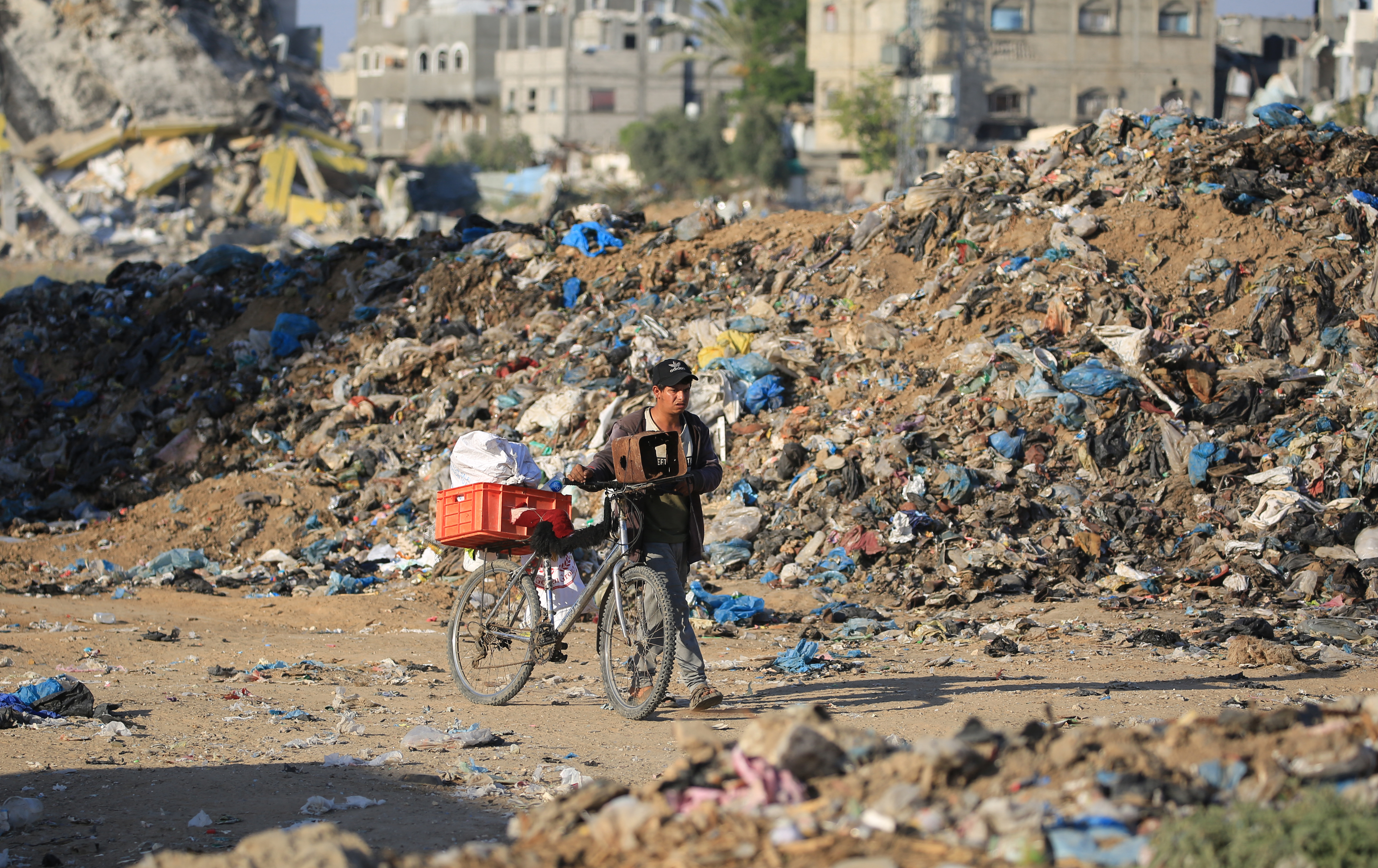 A Palestinian youth pushes a bicycle past a garbage dump at al-Maghazi refugee camp in the central Gaza Strip