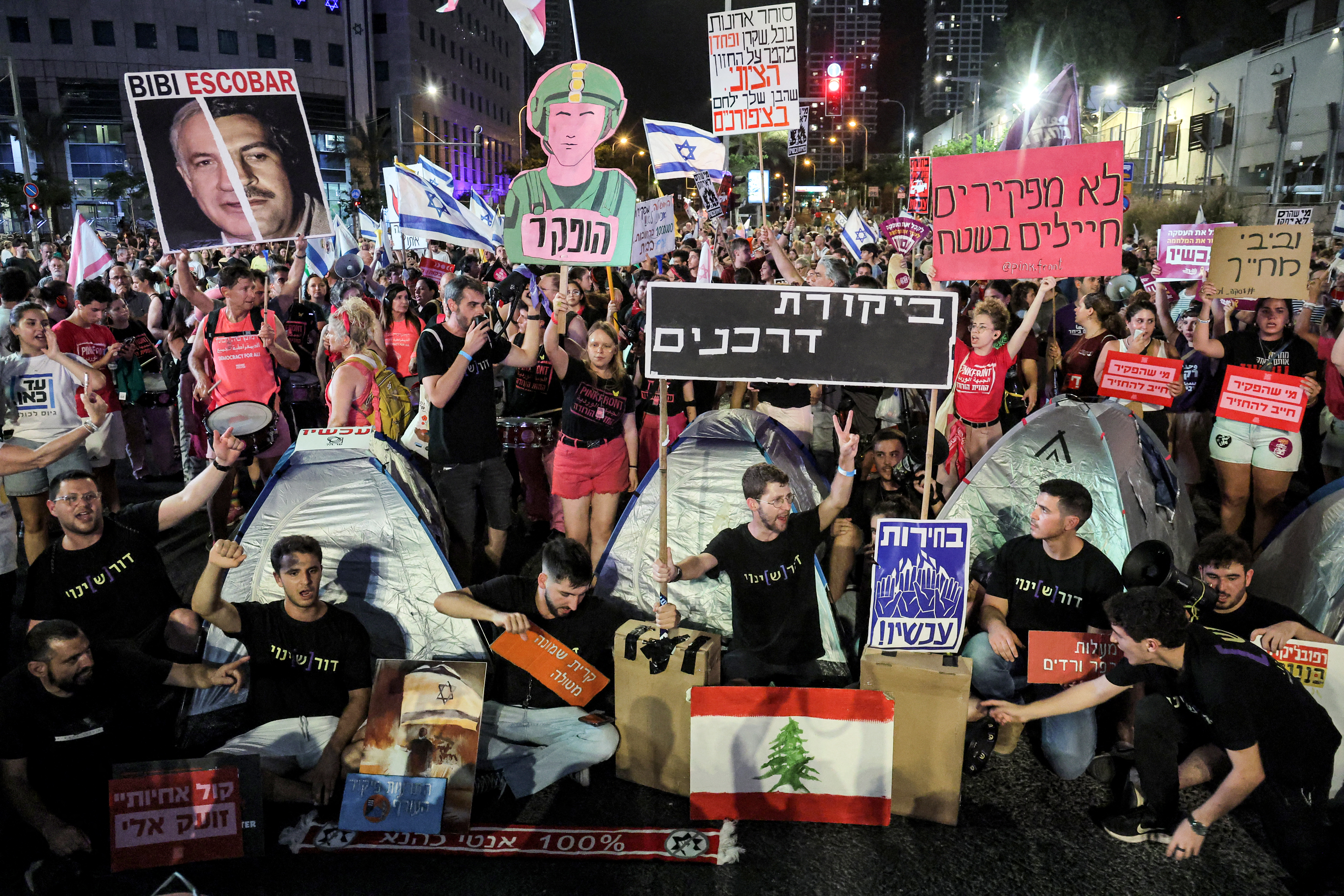people at a protest with Lebanese flags and signs in Hebrew