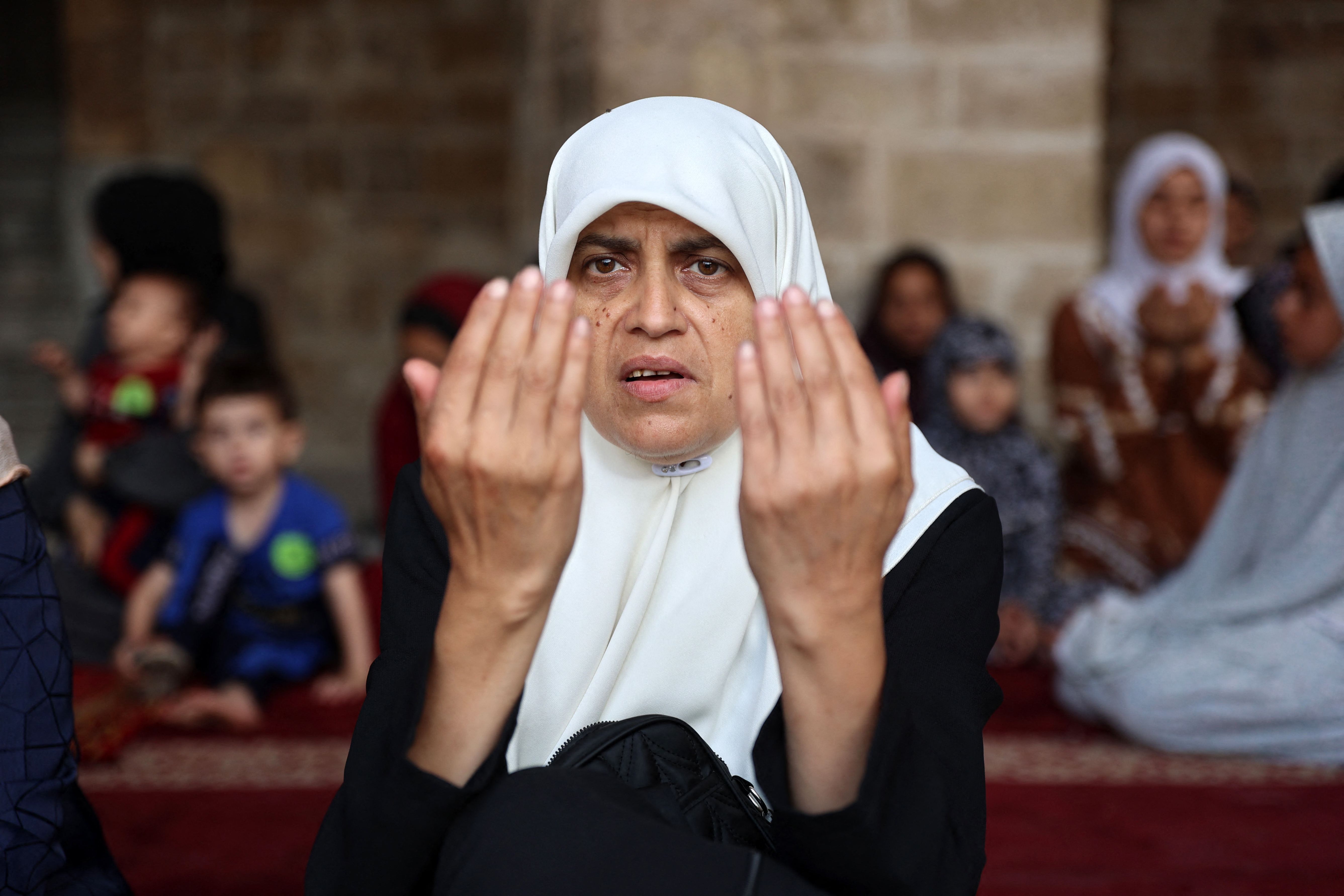 A Palestinian woman performs the Eid al-Adha morning prayer in the courtyard of Gaza City's historic Omari Mosque, which was heavily damaged in Israeli bombardment during the ongoing battles between Israel and Hamas, on the first day of the Muslim holiday marking the end of the hajj pilgrimage to Mecca, on June 16