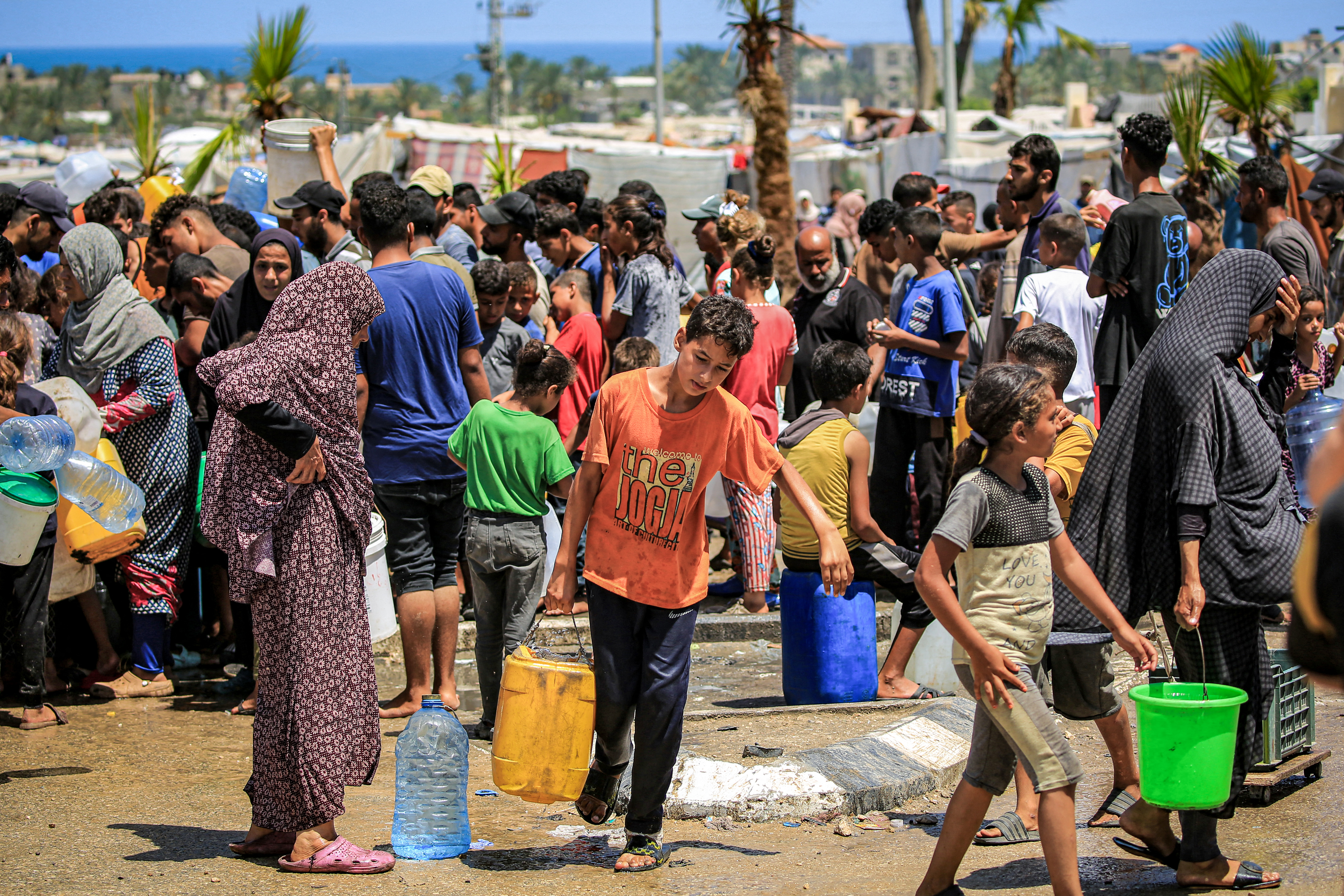 A boy walks with a jerrycan after filling up with others from a truck loaded with water cisterns in Rafah in the southern Gaza Strip