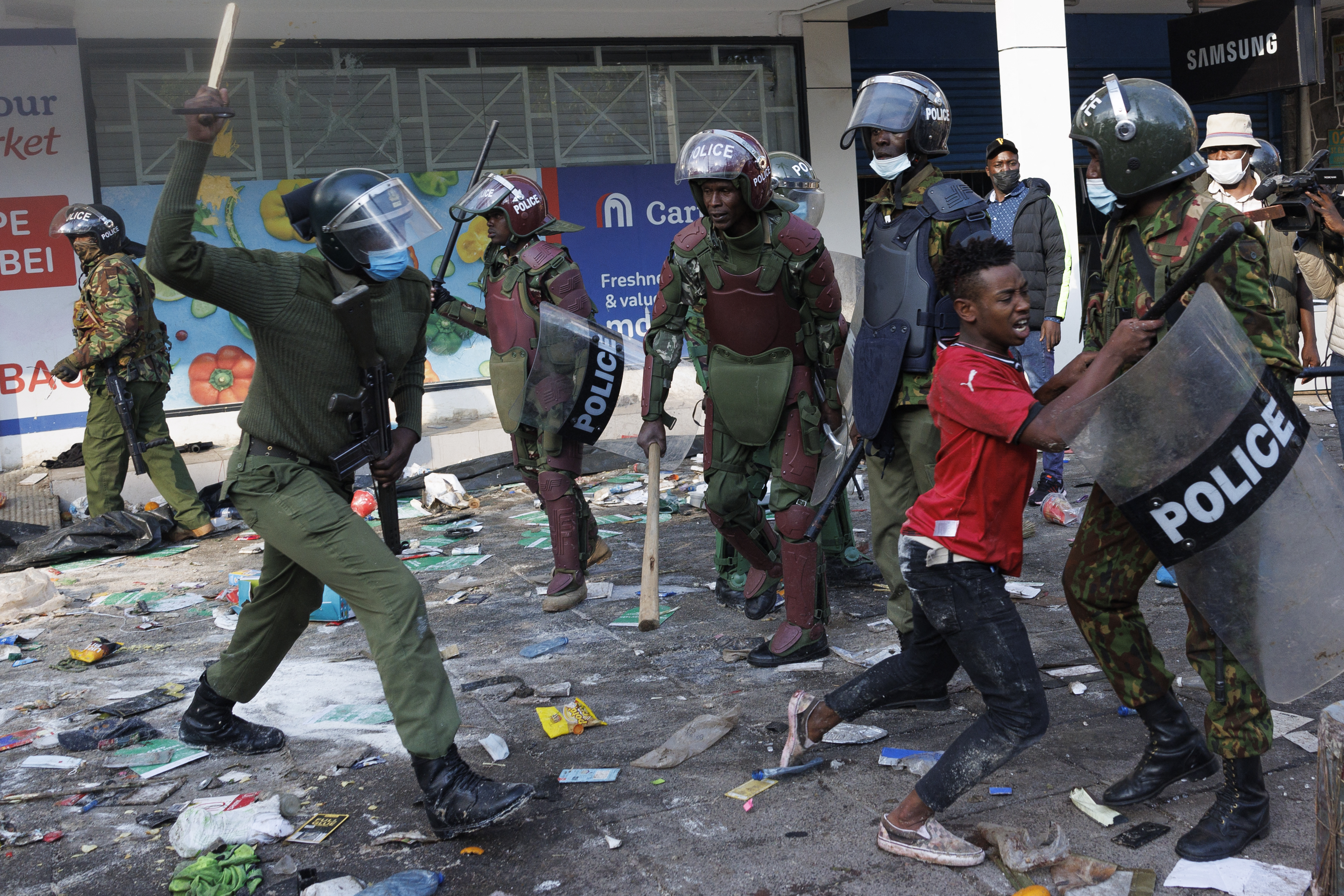 A protester (C) runs from a riot police officer to avoid a police baton during a demonstration in Nairobi