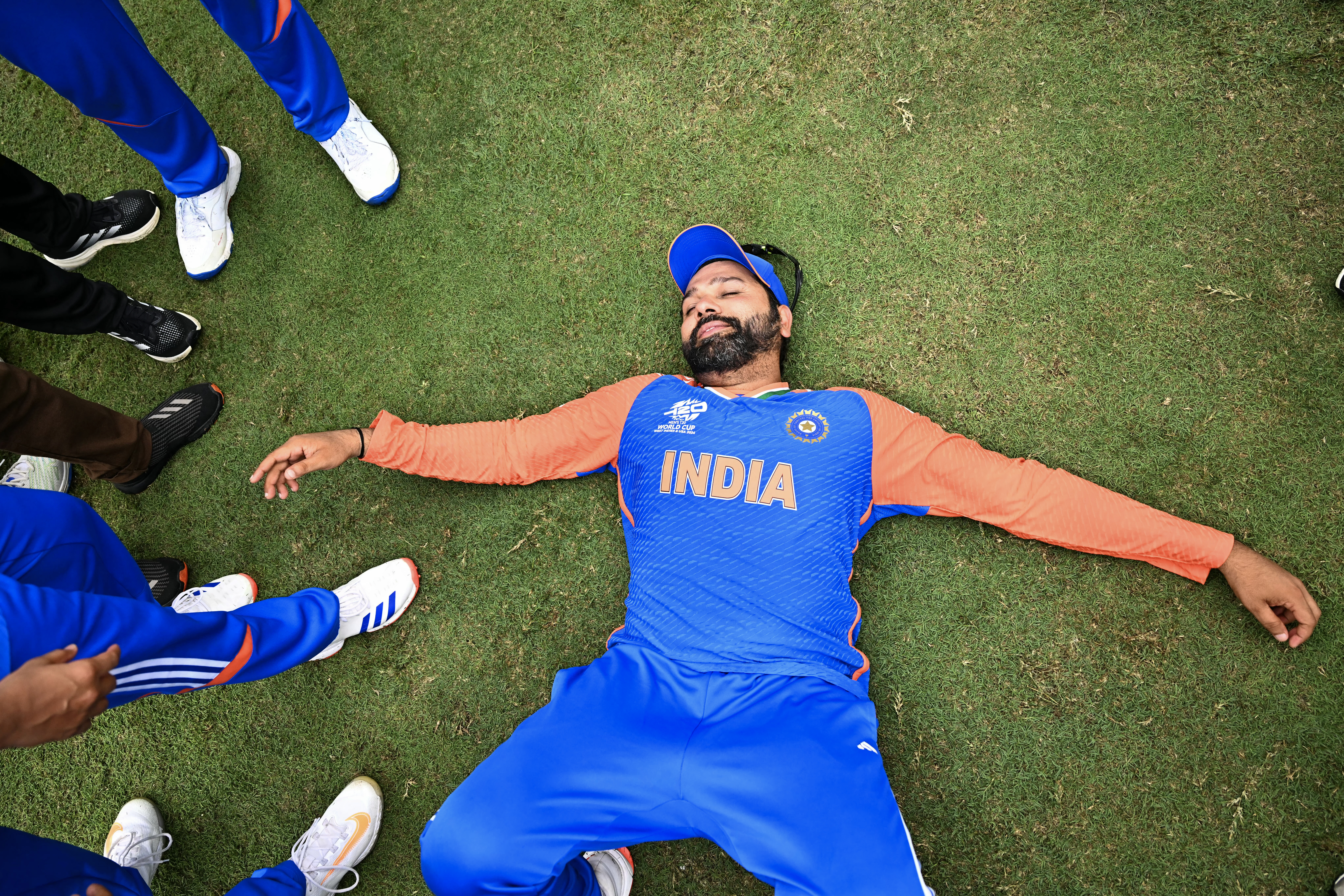 India's captain Rohit Sharma lays on the ground as he celebrates with Team India after winning ICC men's Twenty20 World Cup 2024 final cricket match between India and South Africa at Kensington Oval in Bridgetown, Barbados, on June 29, 2024. (Photo by CHANDAN KHANNA / AFP)