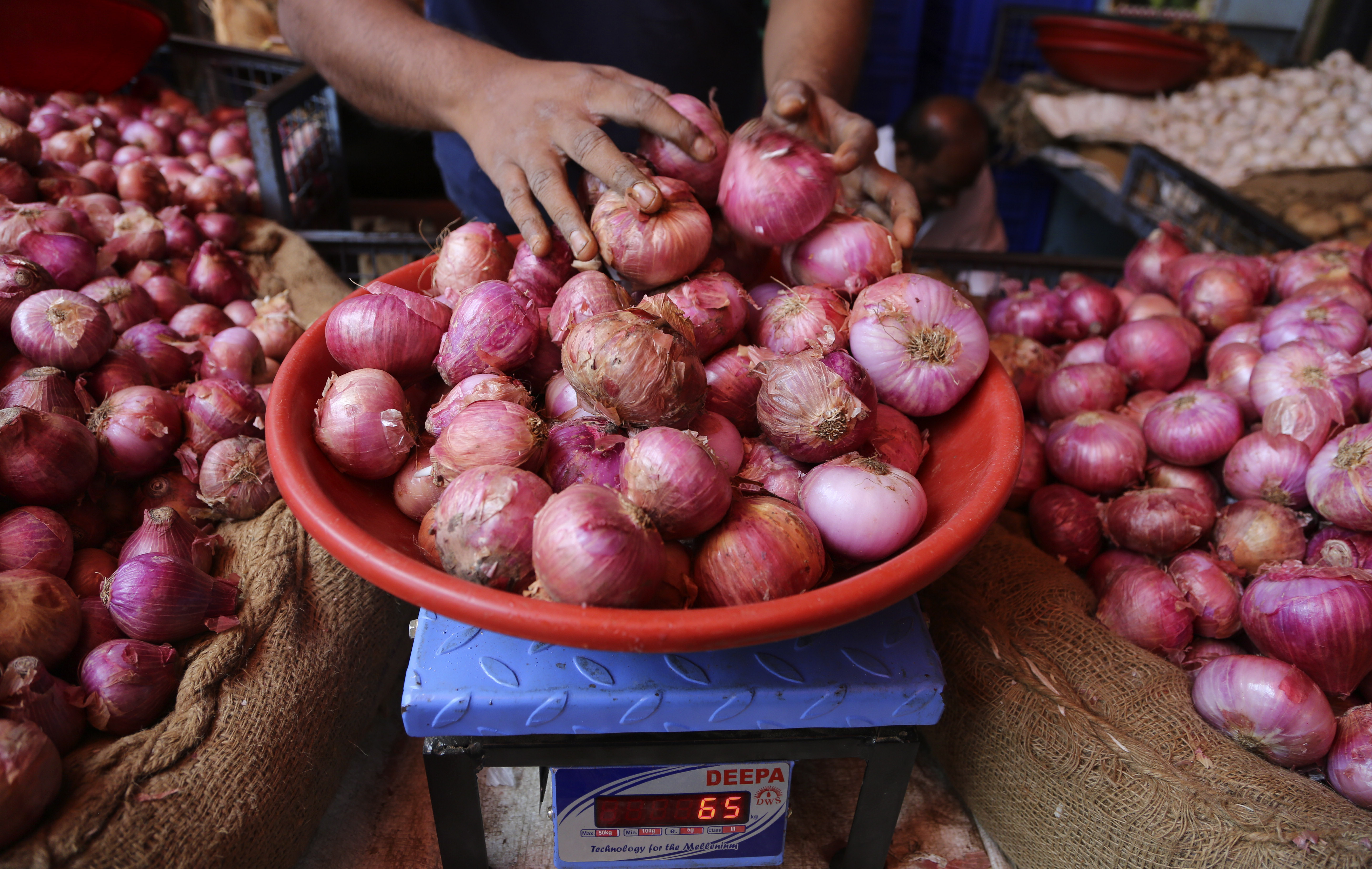 In this Tuesday, Dec. 3, 2019, photo, a vendor weighs onions for a customer at a farmers market in Bangalore, India. Soaring prices has put the humble onion, a staple for most Indian families, out of reach, adding to worries over food inflation at a time when the slowing economy has become a severe liability for Prime Minister Narendra Modi's government. Onion prices are seen by some as a key indicator of economic stability in India, and opposition parties, quick to smell an opportunity, have rallied in the streets wearing onion garlands and offering onions as wedding gifts. (AP Photo/Aijaz Rahi)