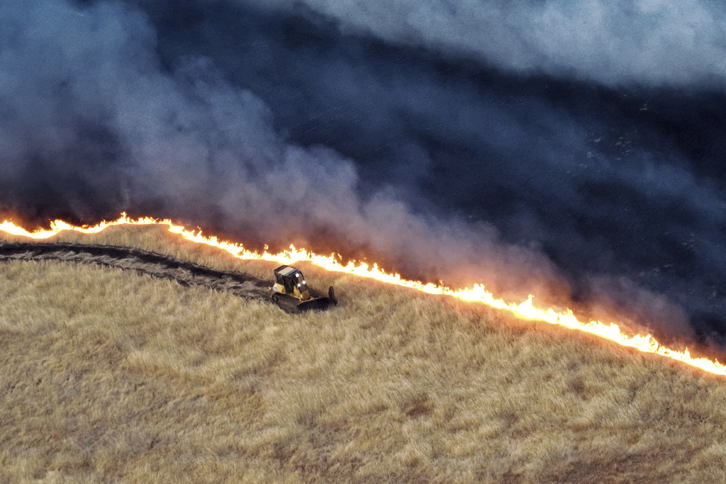 A bulldozer workers to create a line against a fire
