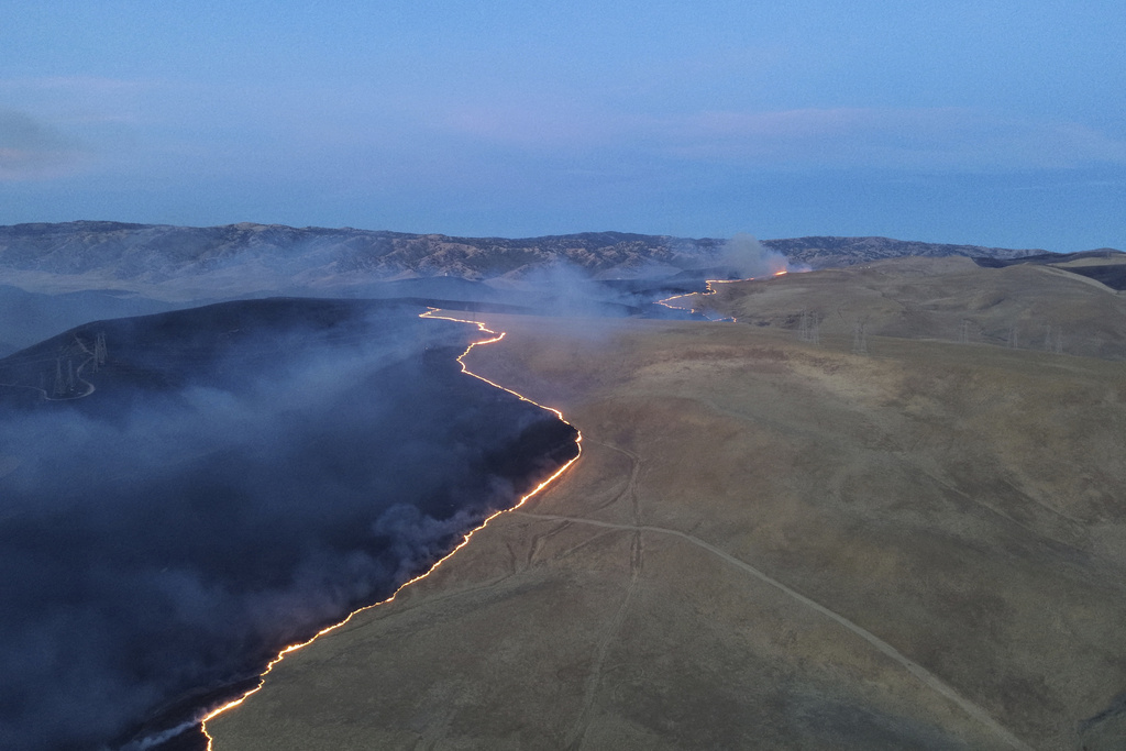 An aerial shot of a wildfire advancing across grassland