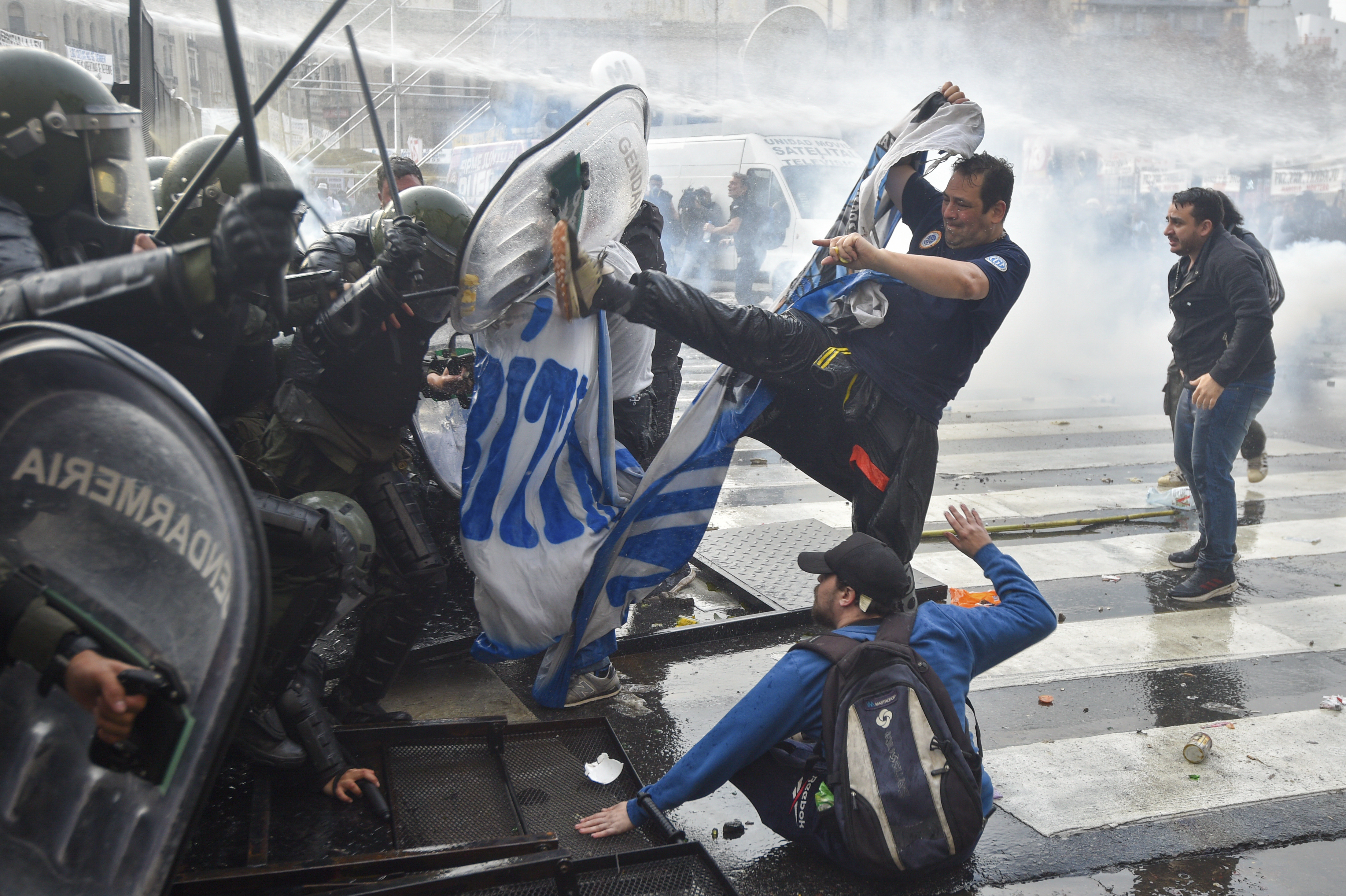 A man kicks a line of riot police through their clear plastic shields.
