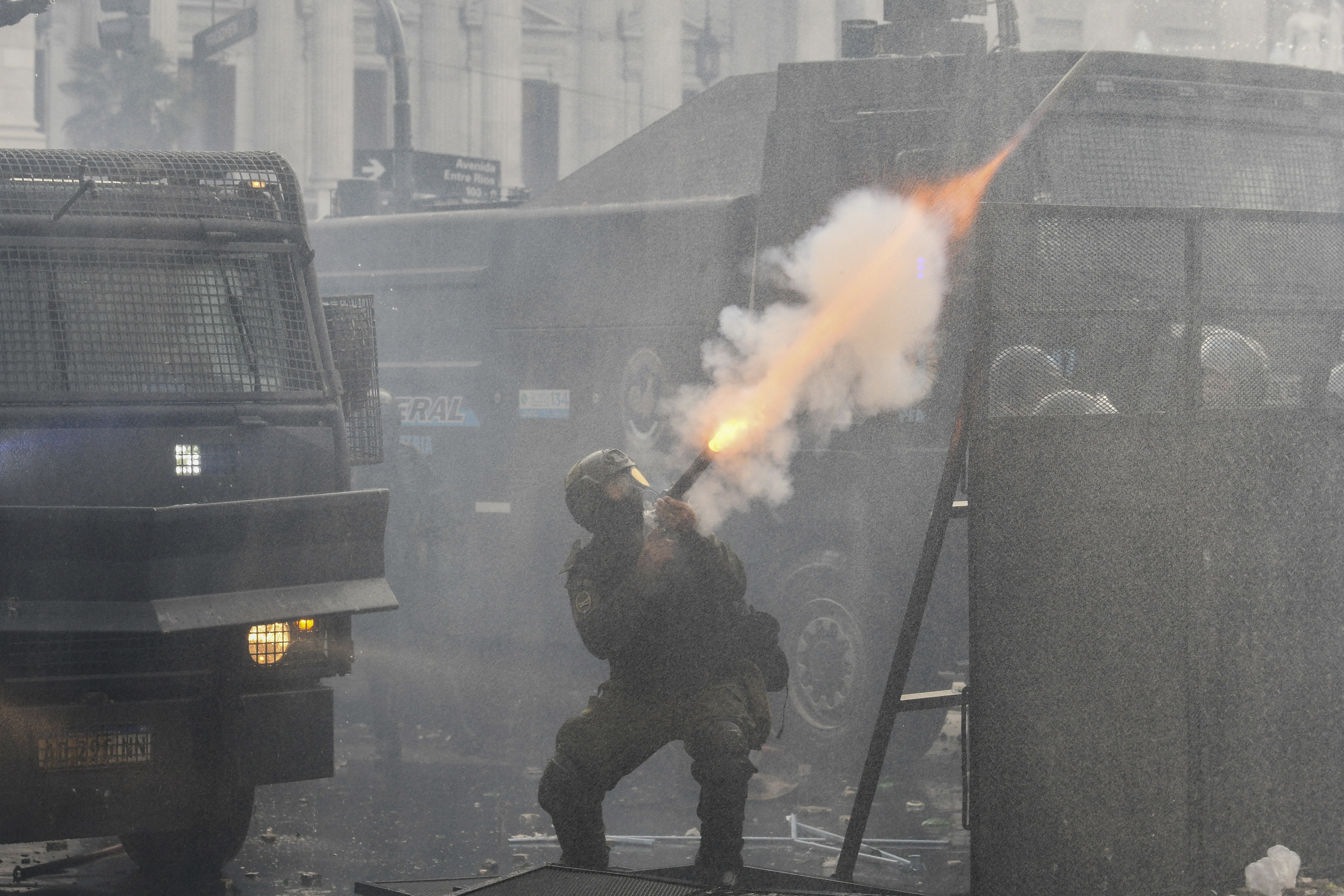 A police officer launches a canister of gas into the air.