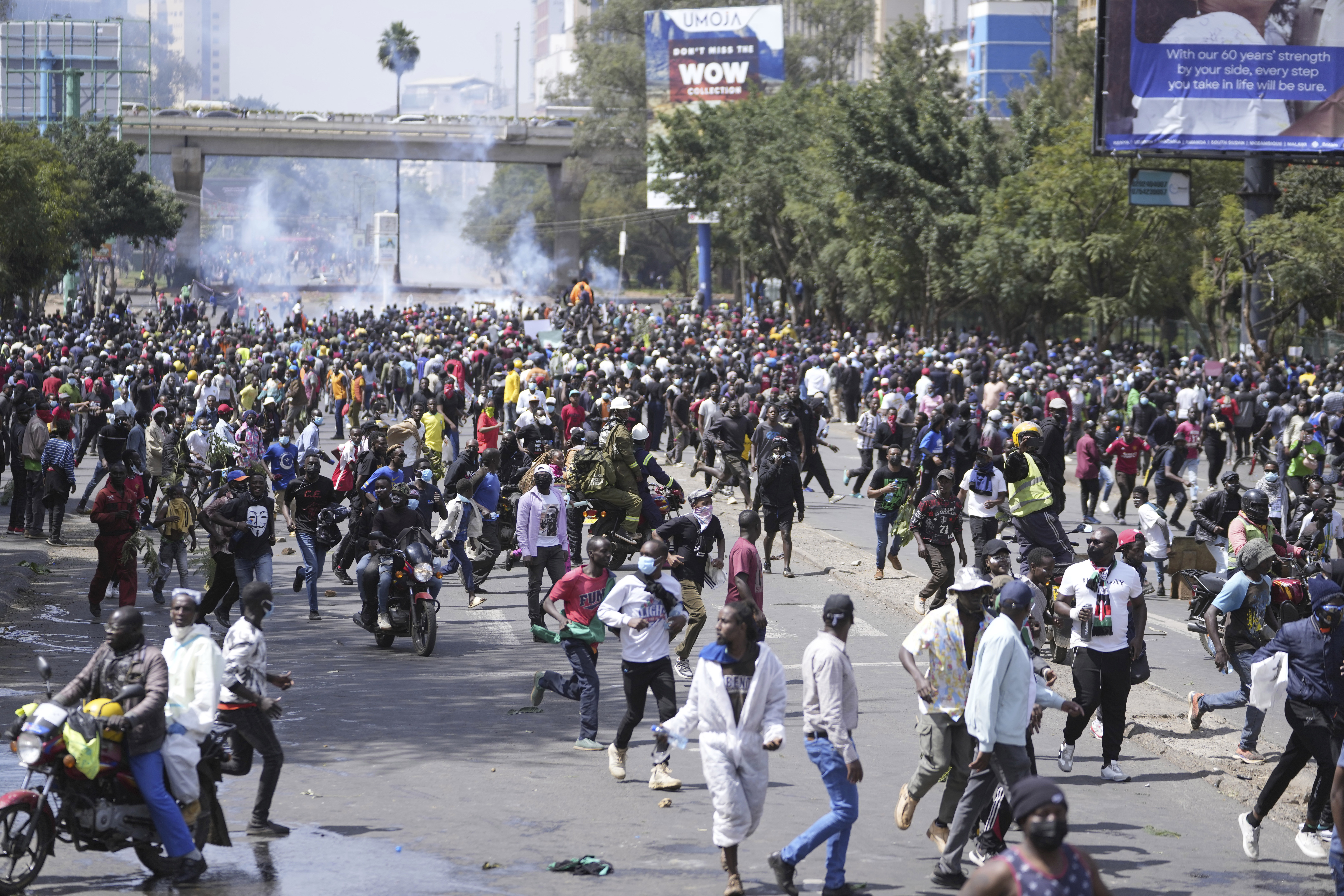 Protesters scatter as Kenya police spray water canon at them during a protest over proposed tax hikes in a finance bill in downtown Nairobi, Kenya