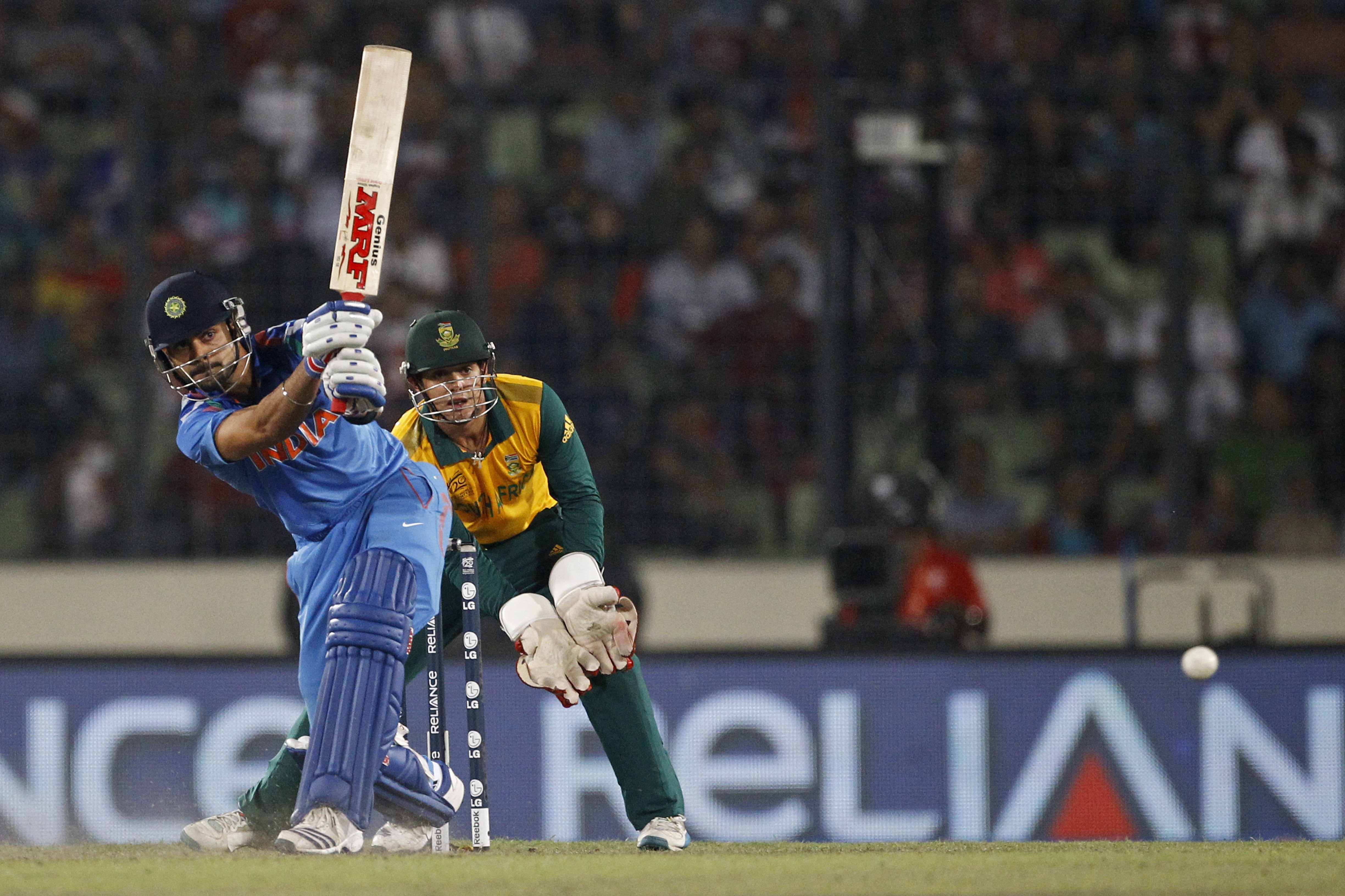 India's Virat Kohli plays a shot, as South Africa's wicketkeeper Quinton de Kock watches during their ICC Twenty20 Cricket World Cup semifinal match in Dhaka, Bangladesh, Friday, April 4, 2014.(AP Photo/A.M. Ahad)
