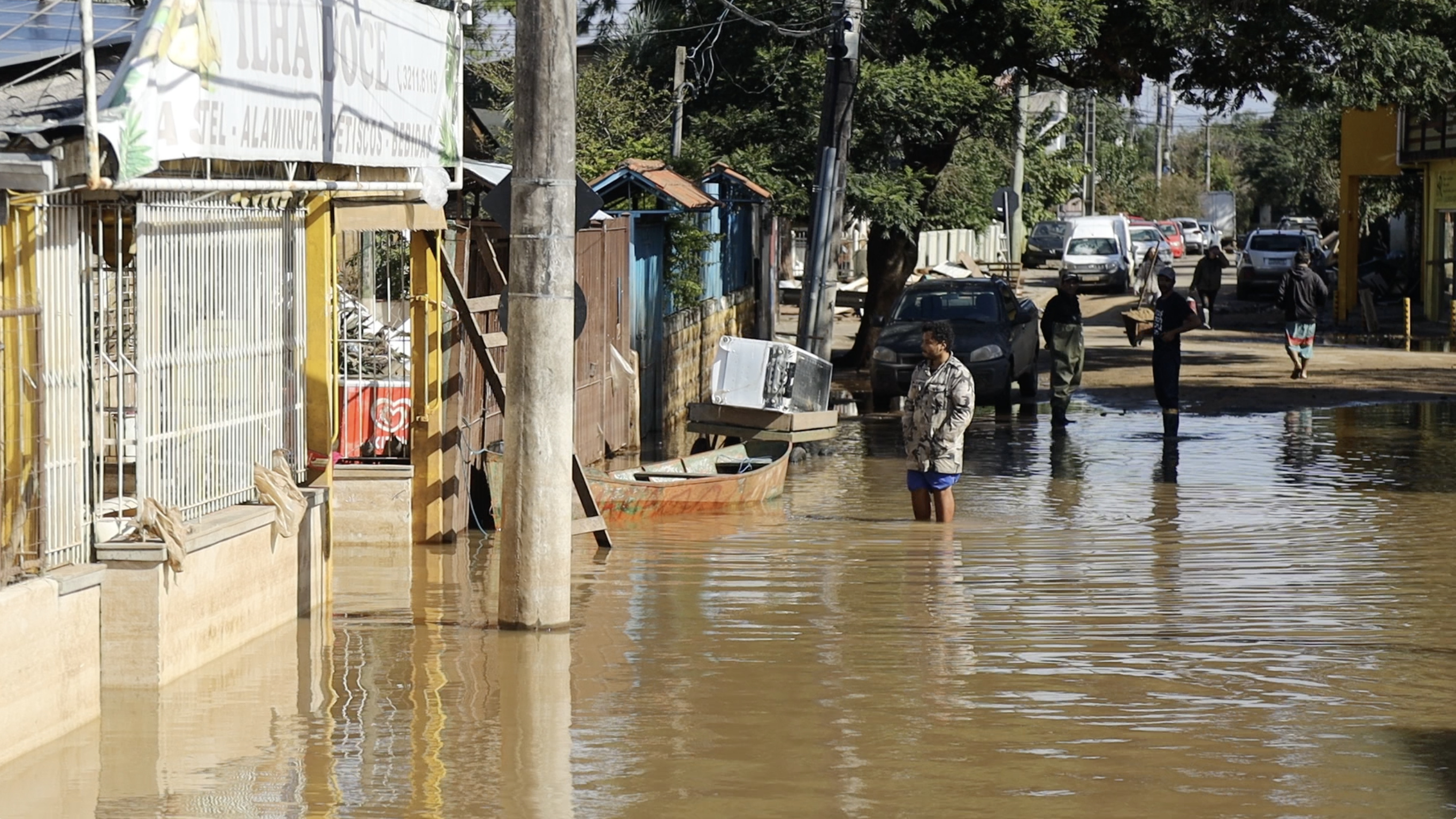 A man wades through muddy flood water, walking down the street of the Ilhas neighbourhood of Porto Alegre.