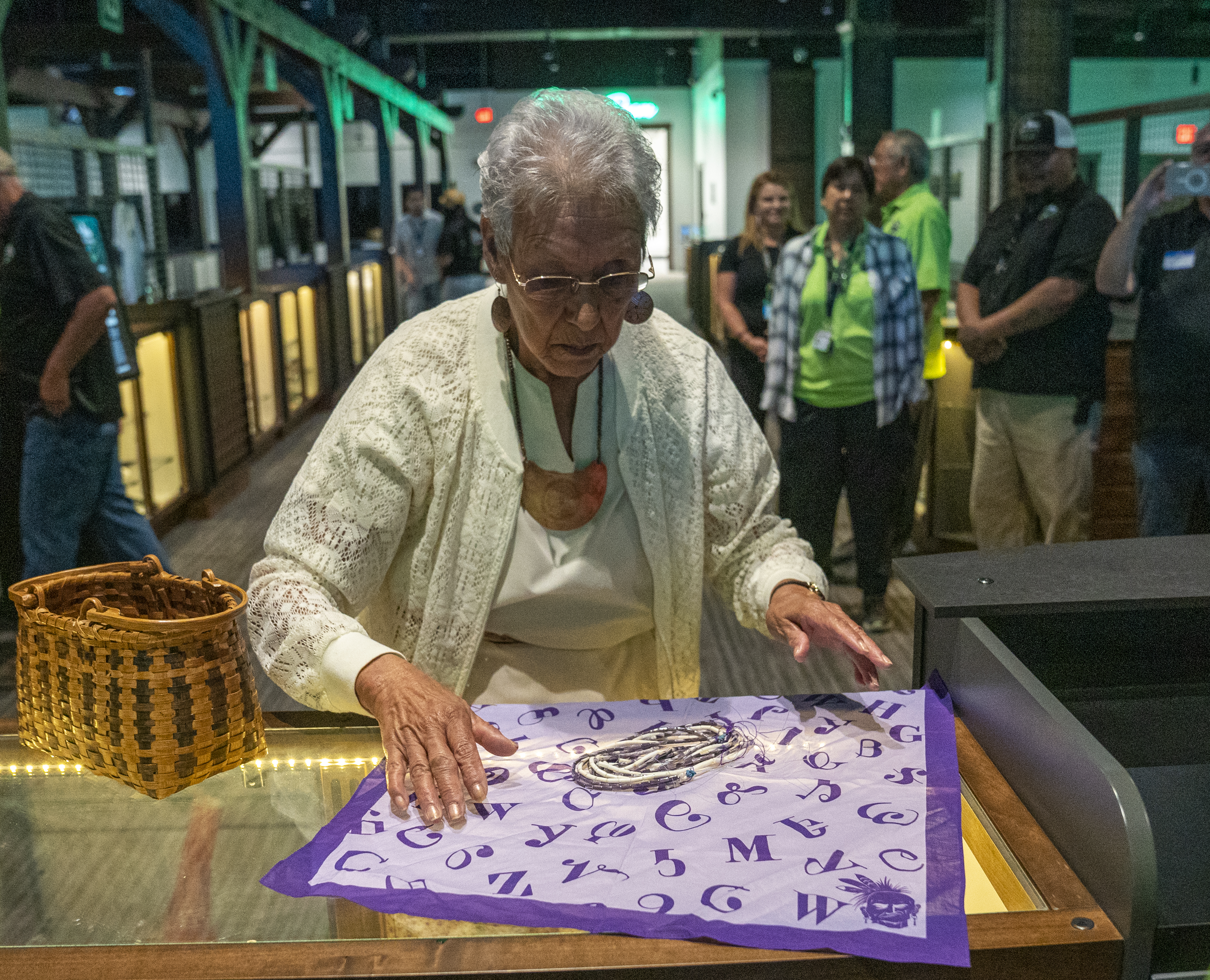 Myrtle Driver, a Beloved Woman and tribal elder, spreads out a purple handkerchief on a table, with strings of wampum beads sitting inside.