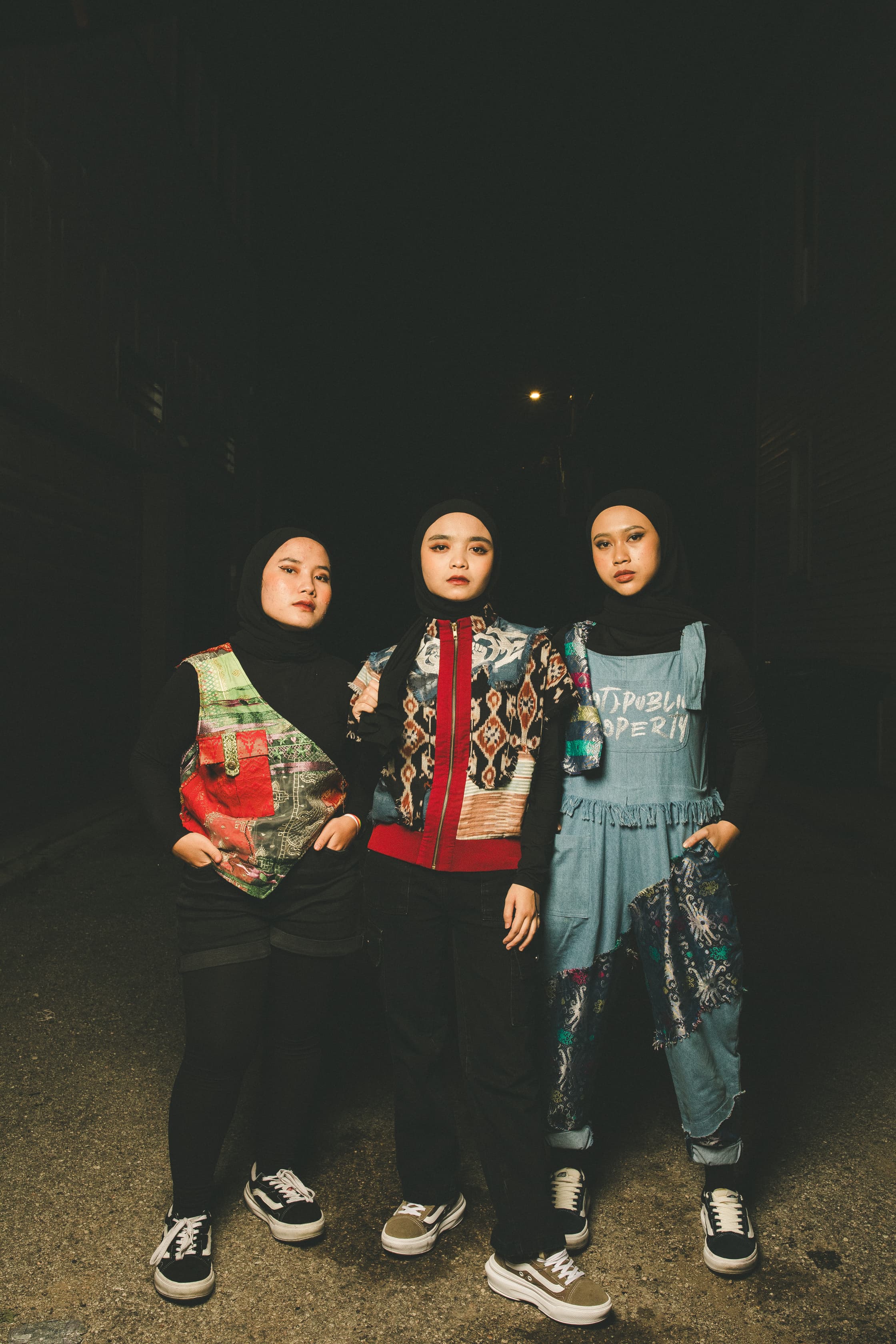 Siti, Marsya and Widi (left to right)/ They are dressed mainly in black with black headscarves. Widi is wearing denim overalls as well, while Siti and Marsya have added a colourful waist coat and jacket respectively
