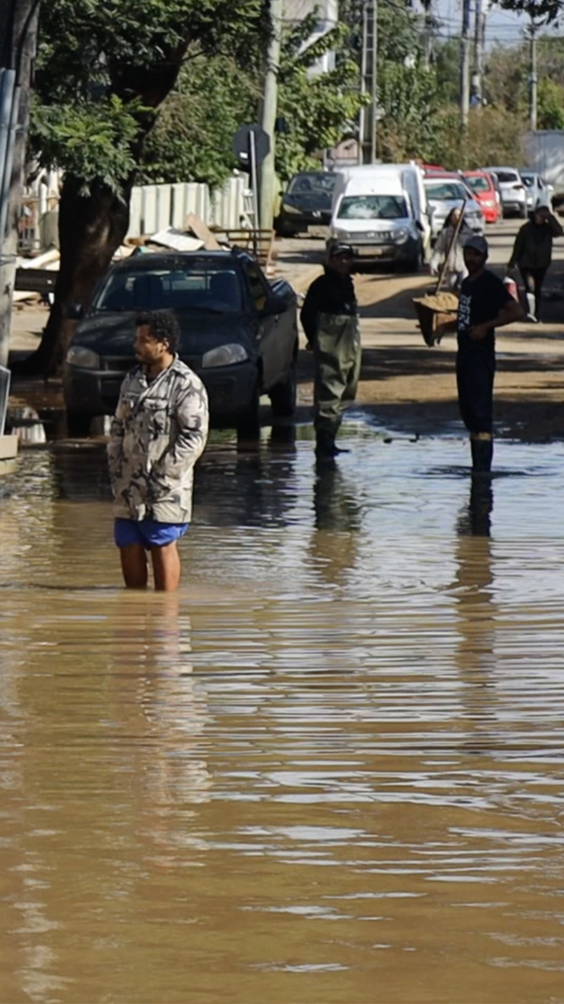 A man wades through muddy flood water, walking down the street of the Ilhas neighbourhood of Porto Alegre.