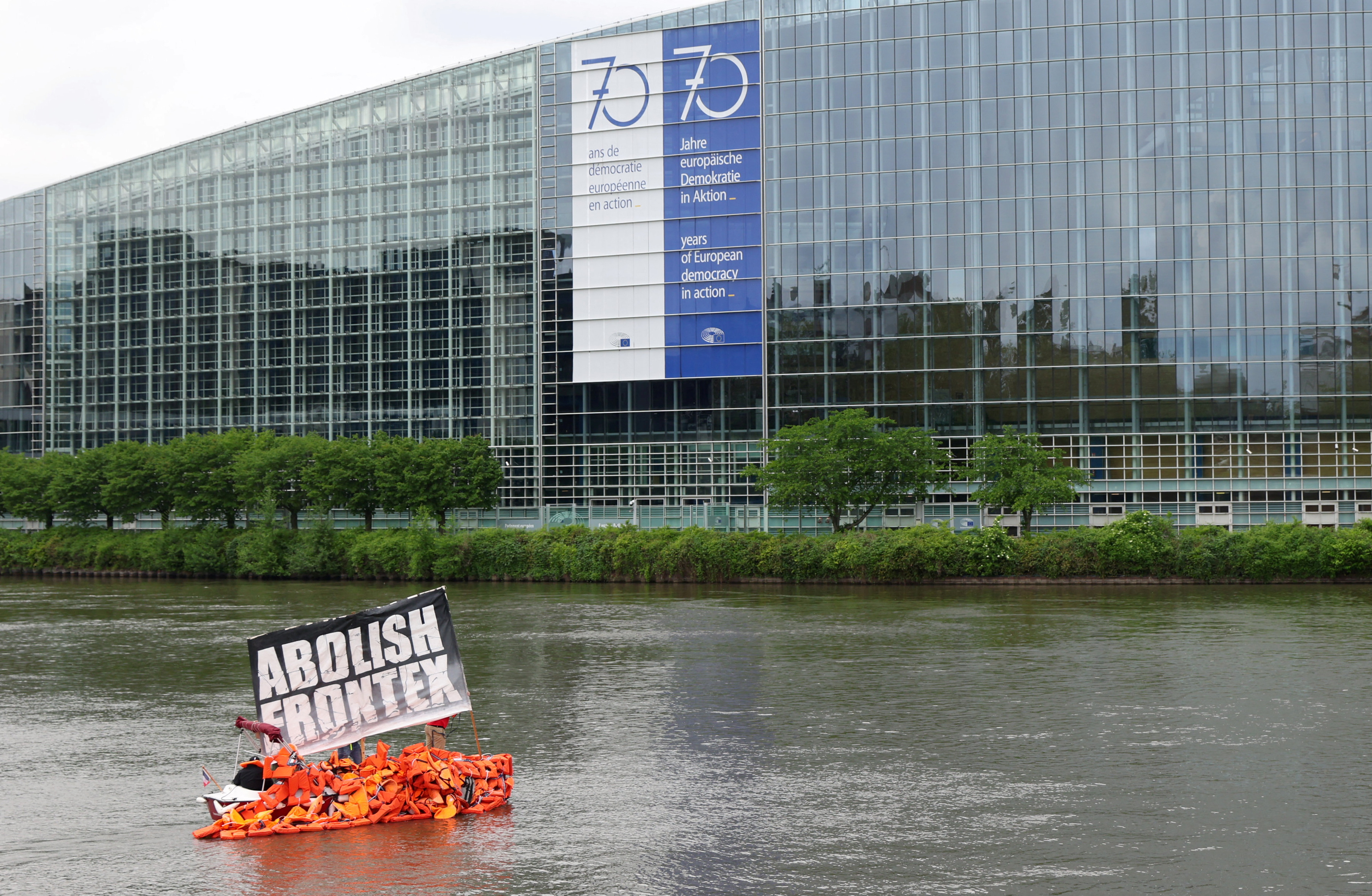 Members of German NGO migrant rescue Sea-Watch and art Kollektiv Ohne Namen sail a boat with life vests during a symbolic art action to bring attention to the plight of refugees crossing the Mediterranean Sea, on the Ill River in front of the European Parliament in Strasbourg, France, May 9, 2023. The slogan reads "Abolish Frontex". REUTERS/Johanna Geron