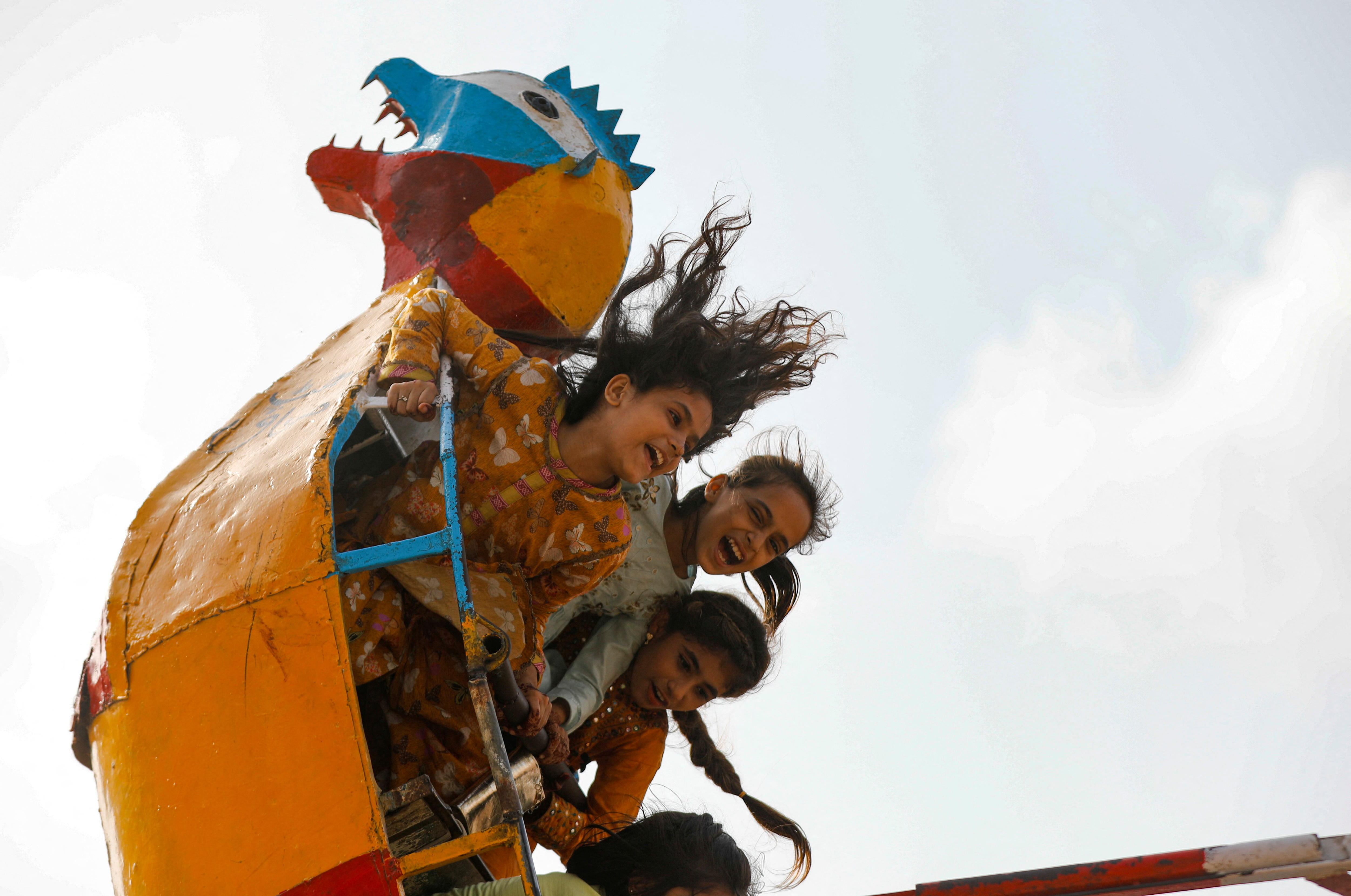 Children react as they ride on swing during Eid al-Adha celebratons in Karachi, Pakistan