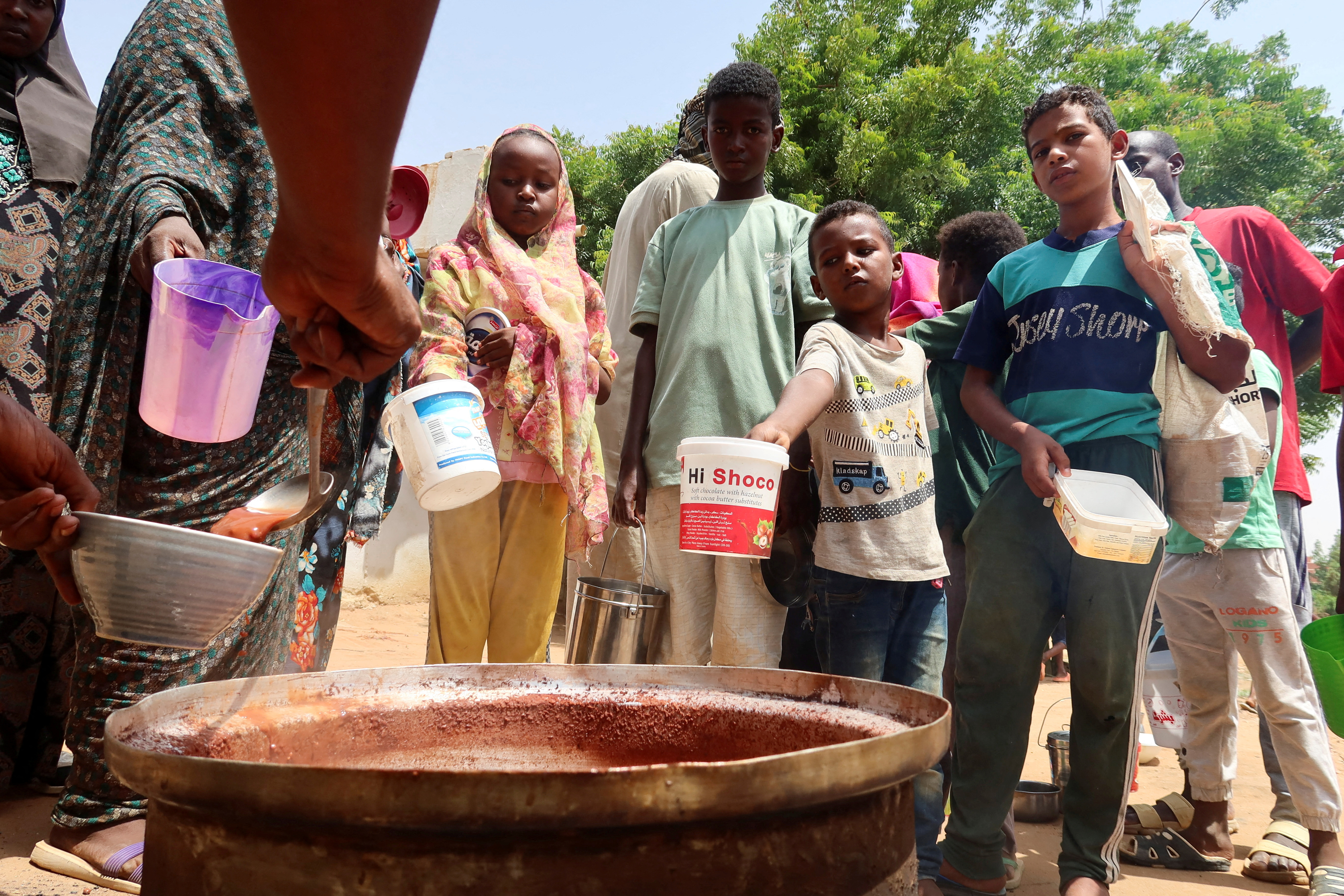 People hold pots as volunteers distribute food in Omdurman, Sudan, September 3, 2023.