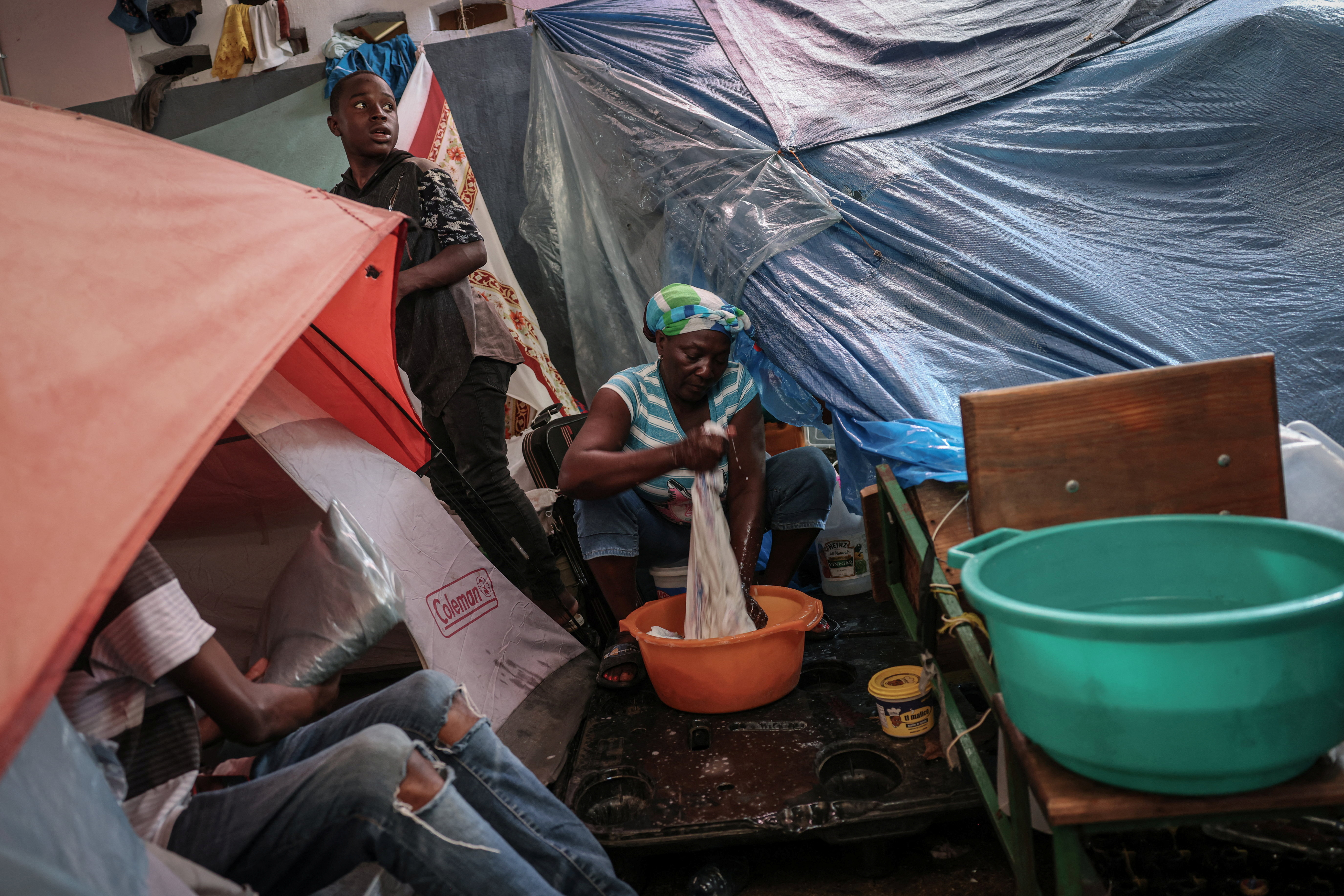 A Haitian woman washes clothes in a tub in a makeshift displacement camp