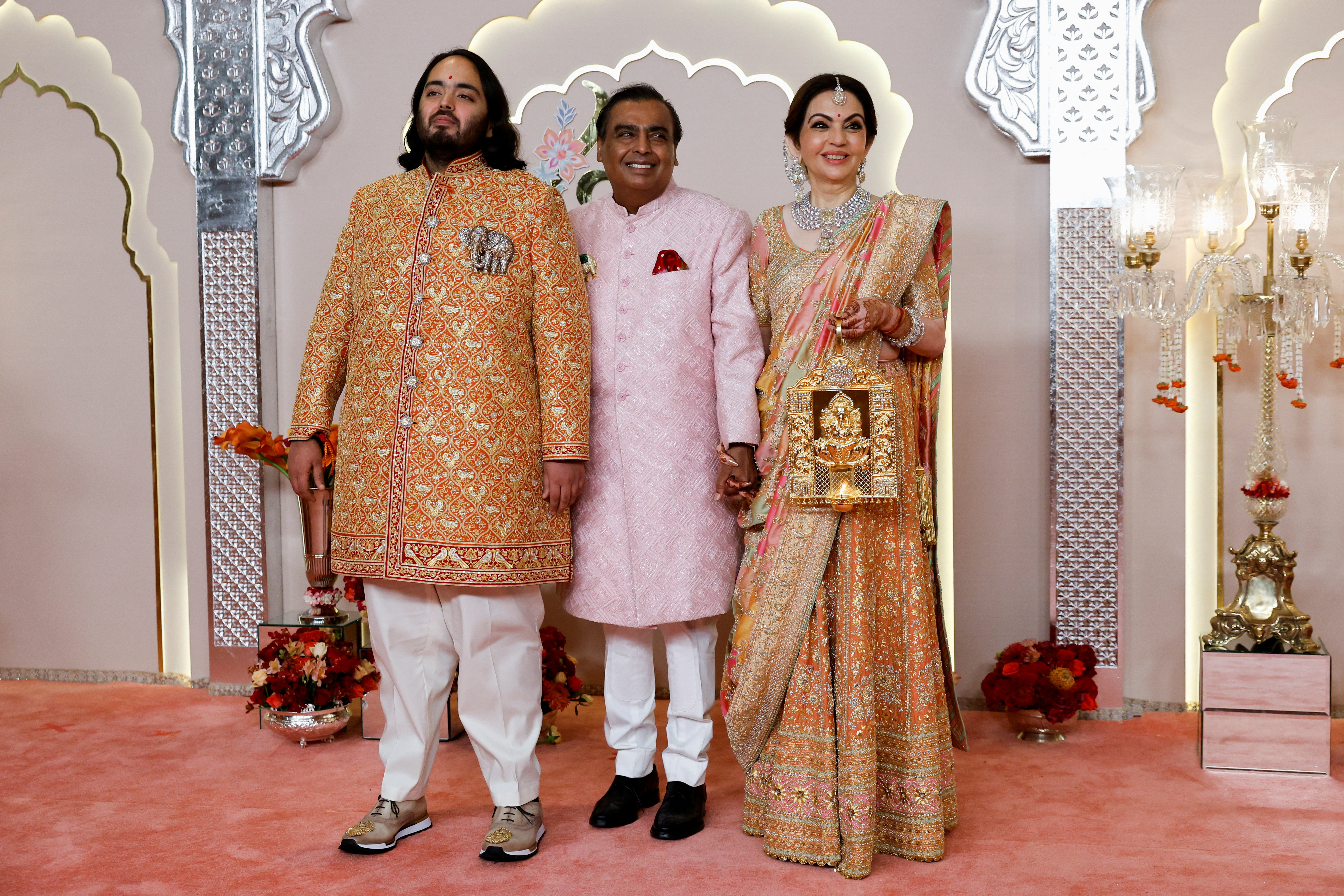 Groom Anant Ambani poses for pictures with Nita Ambani and Mukesh Ambani on the red carpet on the day of his wedding with Radhika Merchant in Mumbai, India