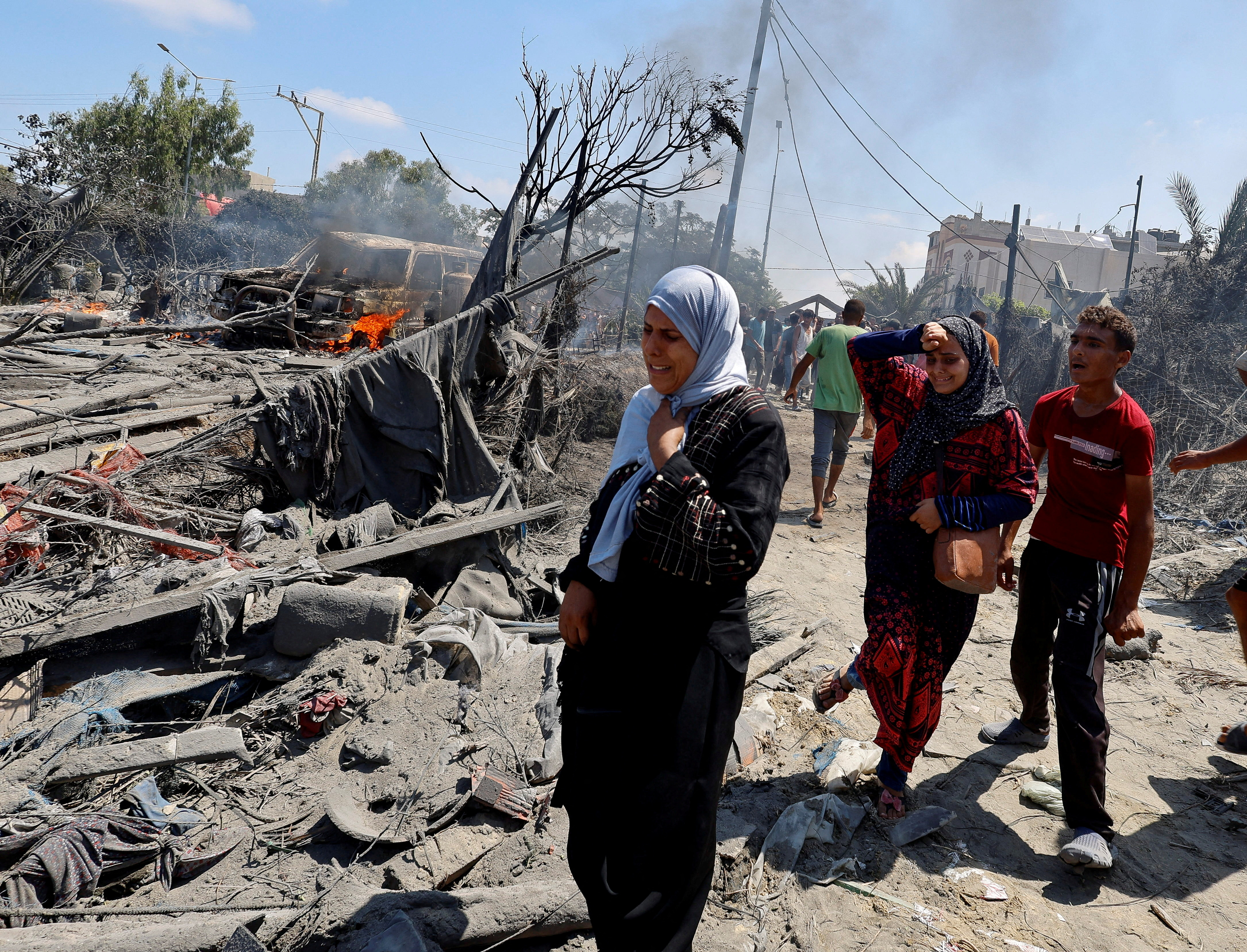 Palestinians react near damage, following what Palestinians say was an Israeli strike at a tent camp in Al-Mawasi area