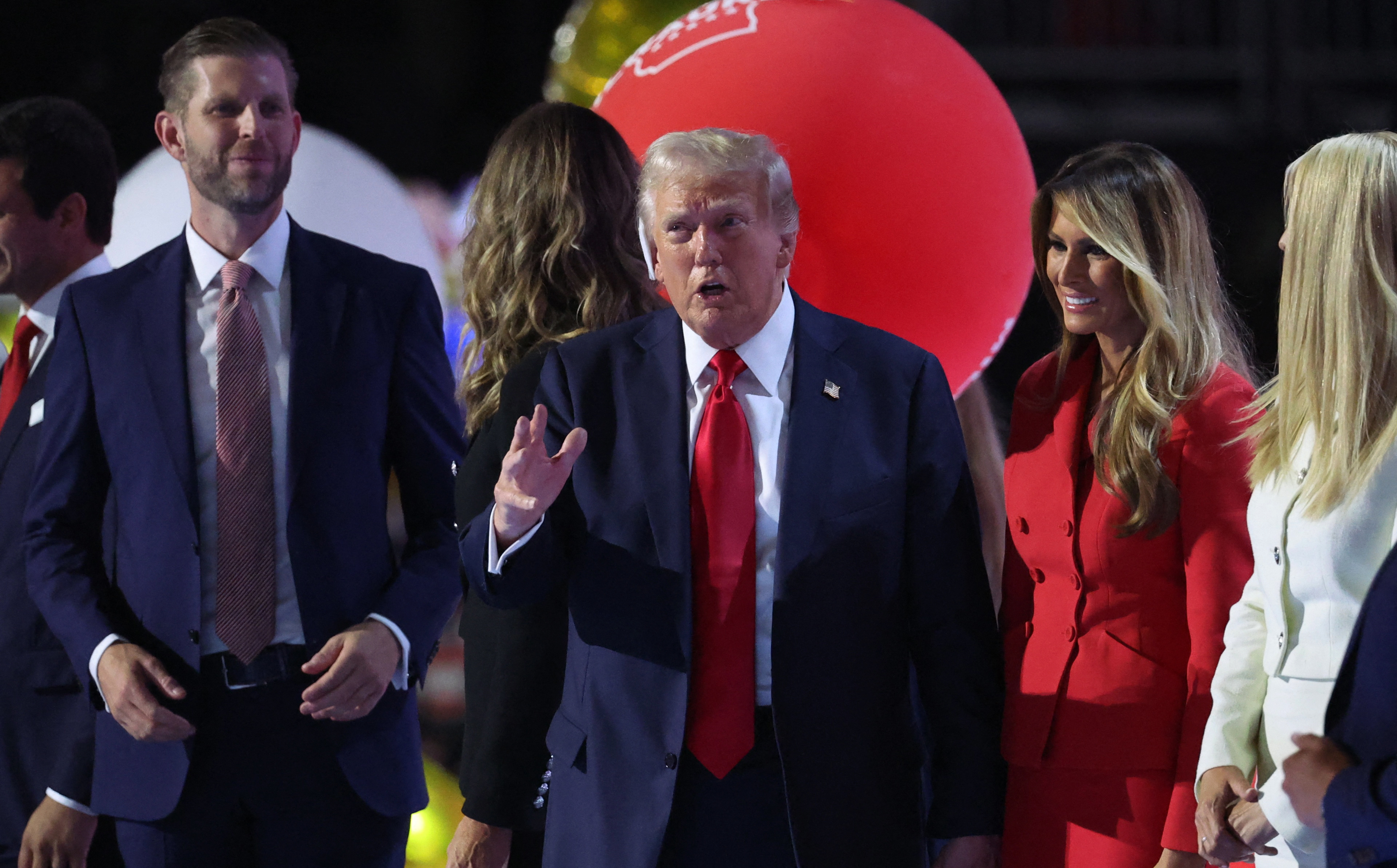 Trump stands on stage as balloons fall at RNC.
