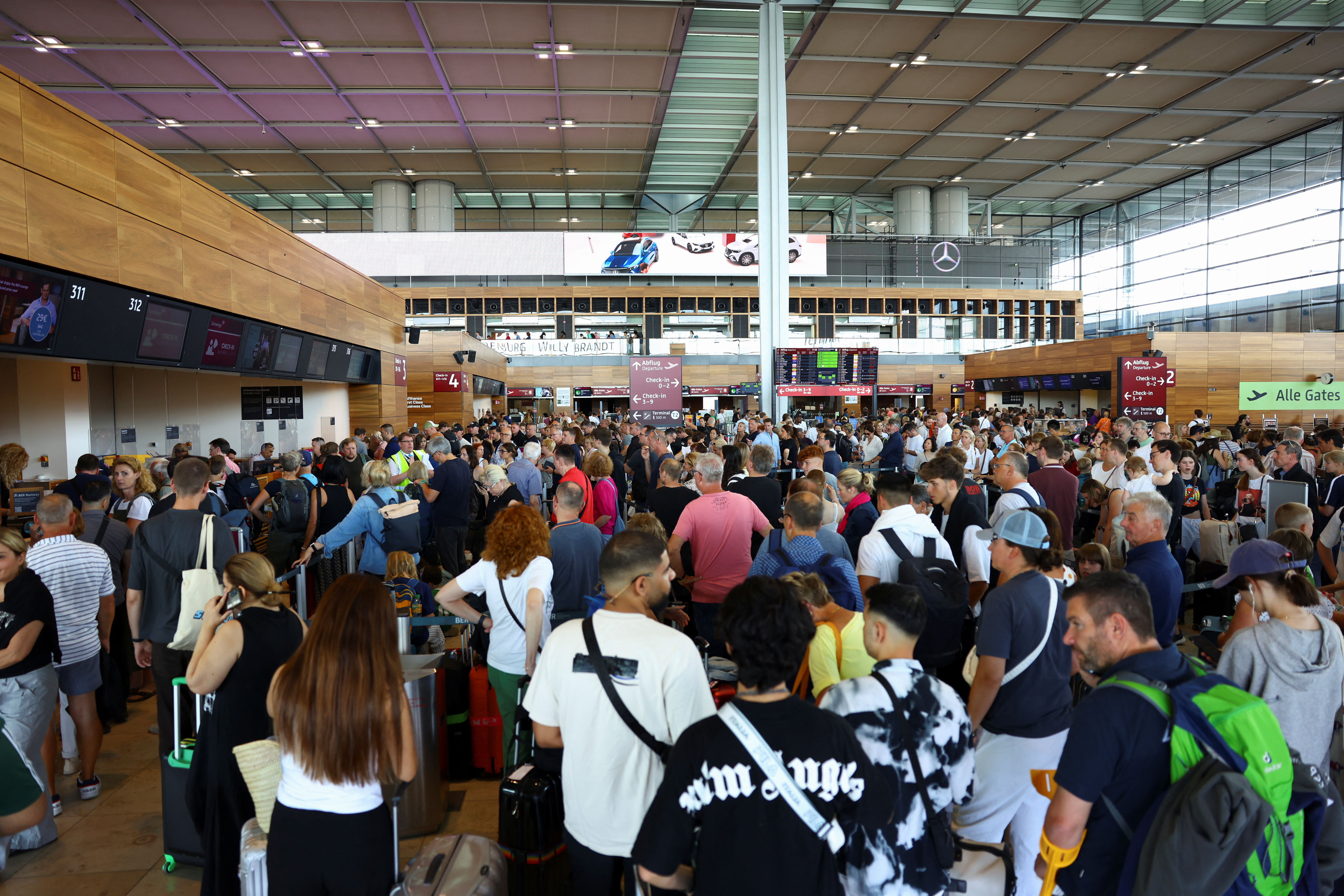 People wait for their flights following a global IT outage, at BER airport in Berlin