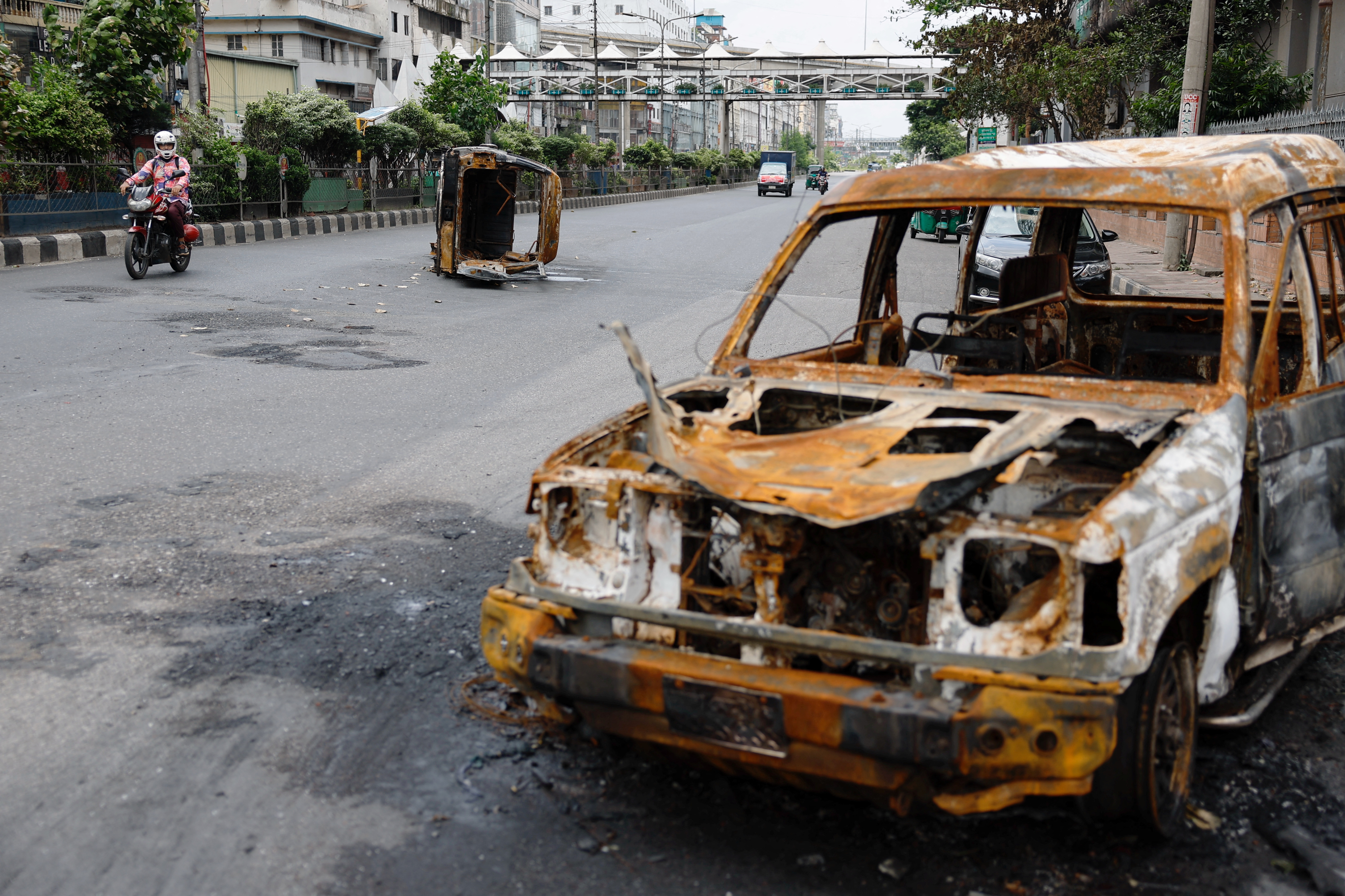 A man rides his motorbike past damaged vehicles