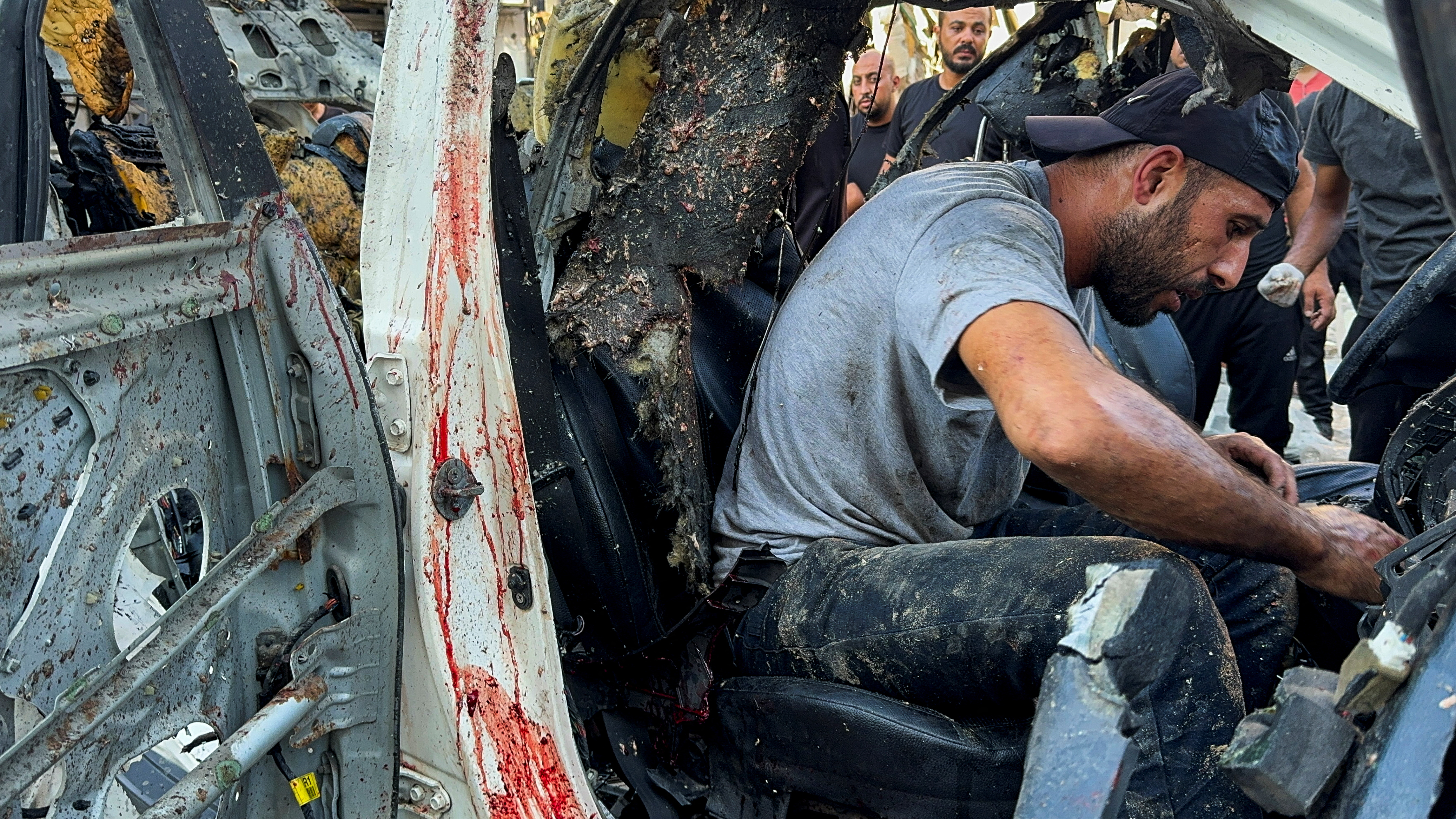 Palestinians inspect a vehicle where Al Jazeera reporter Ismail al-Ghoul and cameraman Ramy El Rify were killed in an Israeli strike