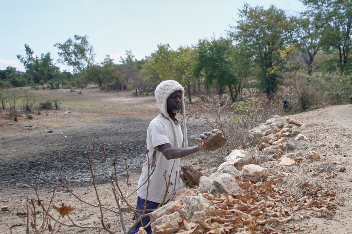 Farmer Takesure Chimbu arranges additional stones to the wall of the Kapotesa dam,