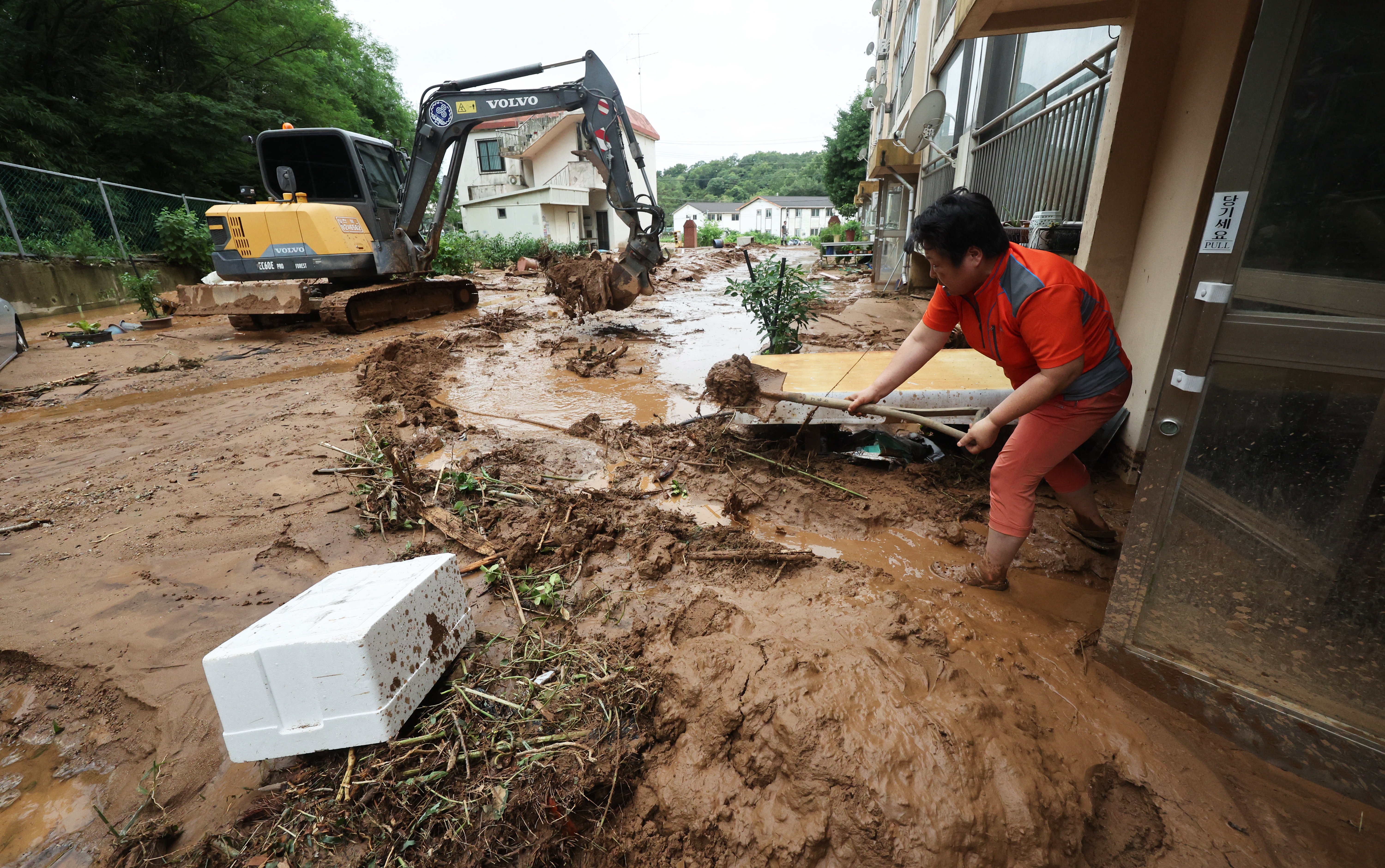 A resident removes mud in front of an apartment building after a landslide