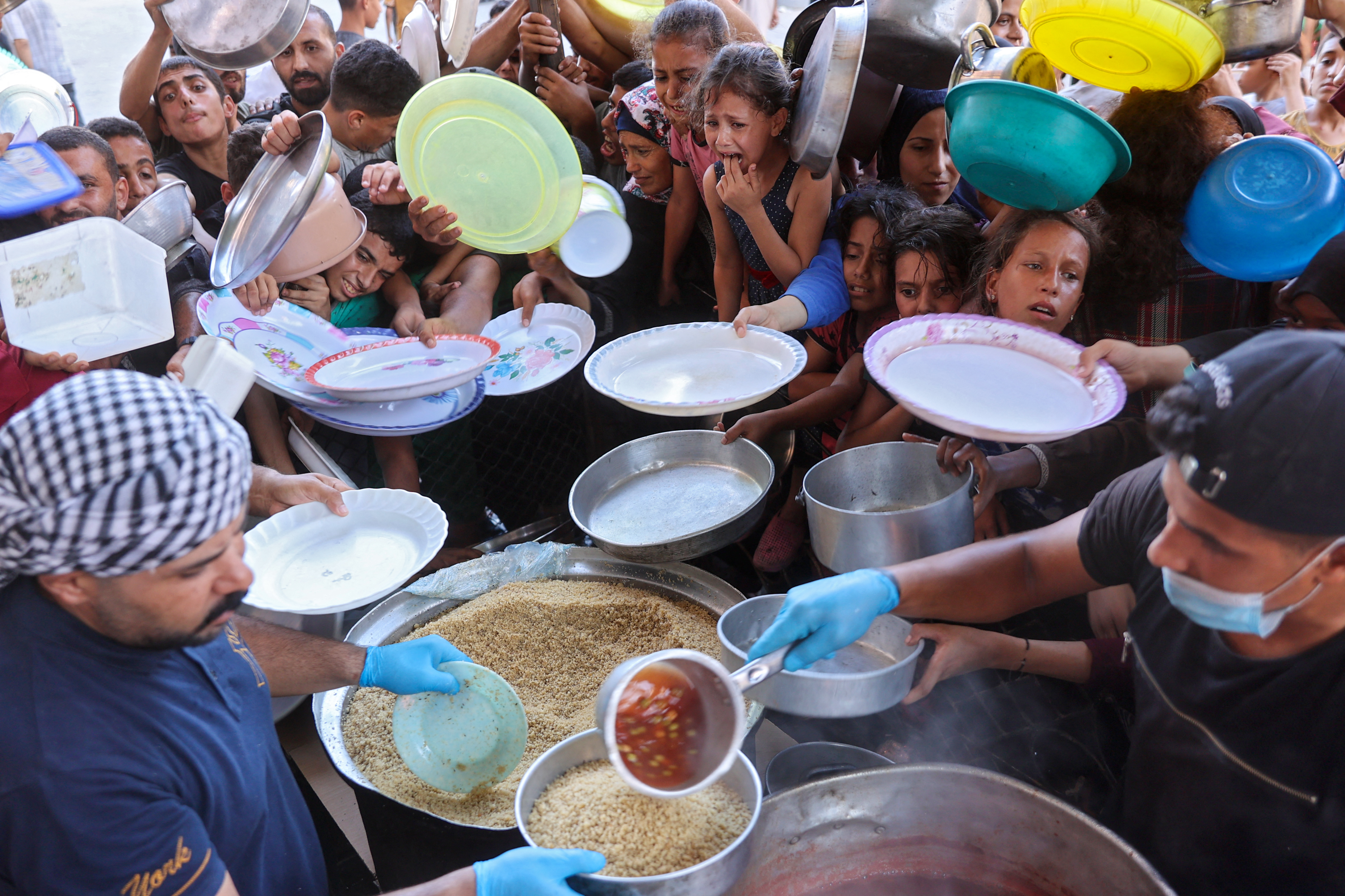 Displaced Palestinians wait to receive food at a distribution point