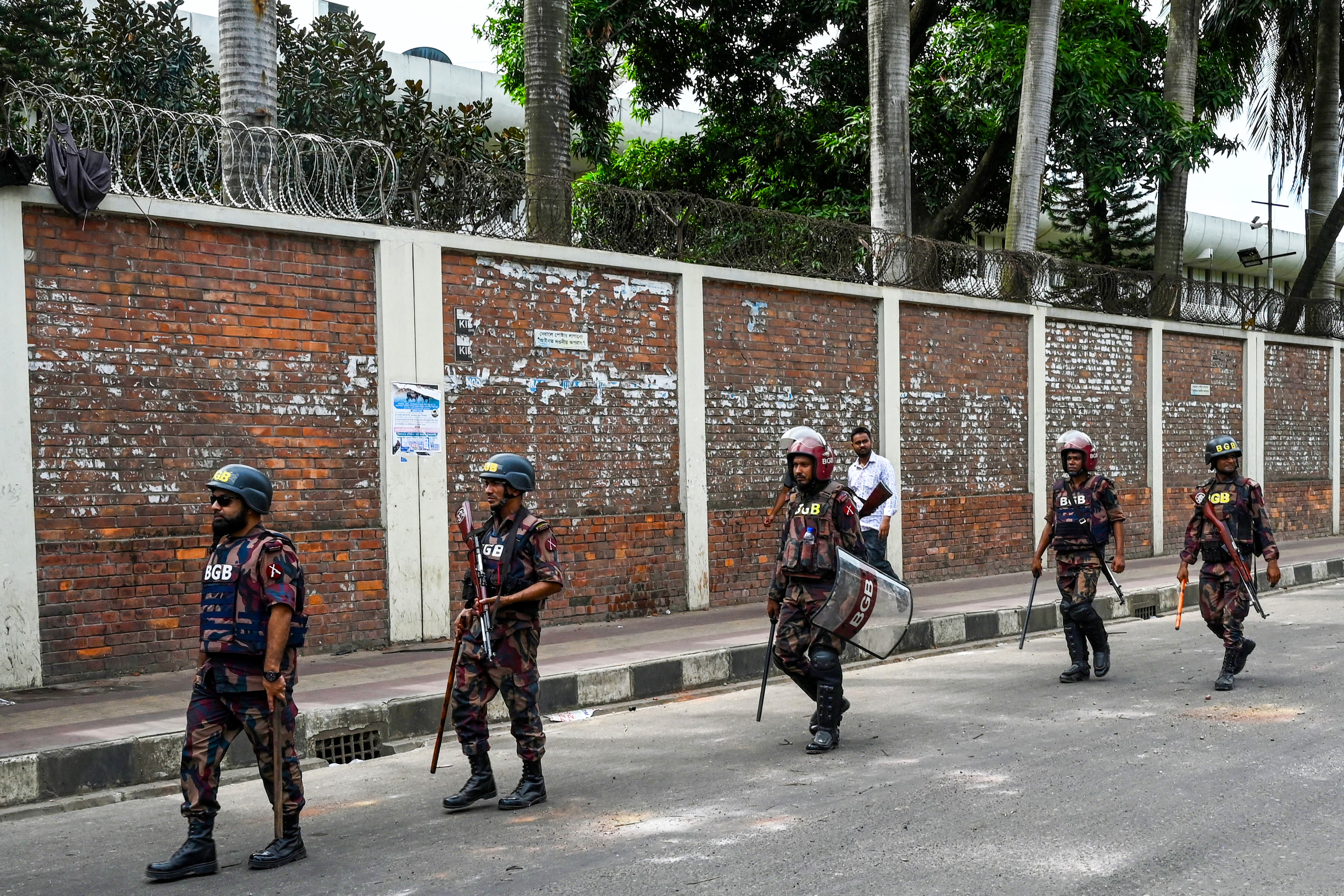 Security personnel walk past the headquarters of state broadcaster Bangladesh Television