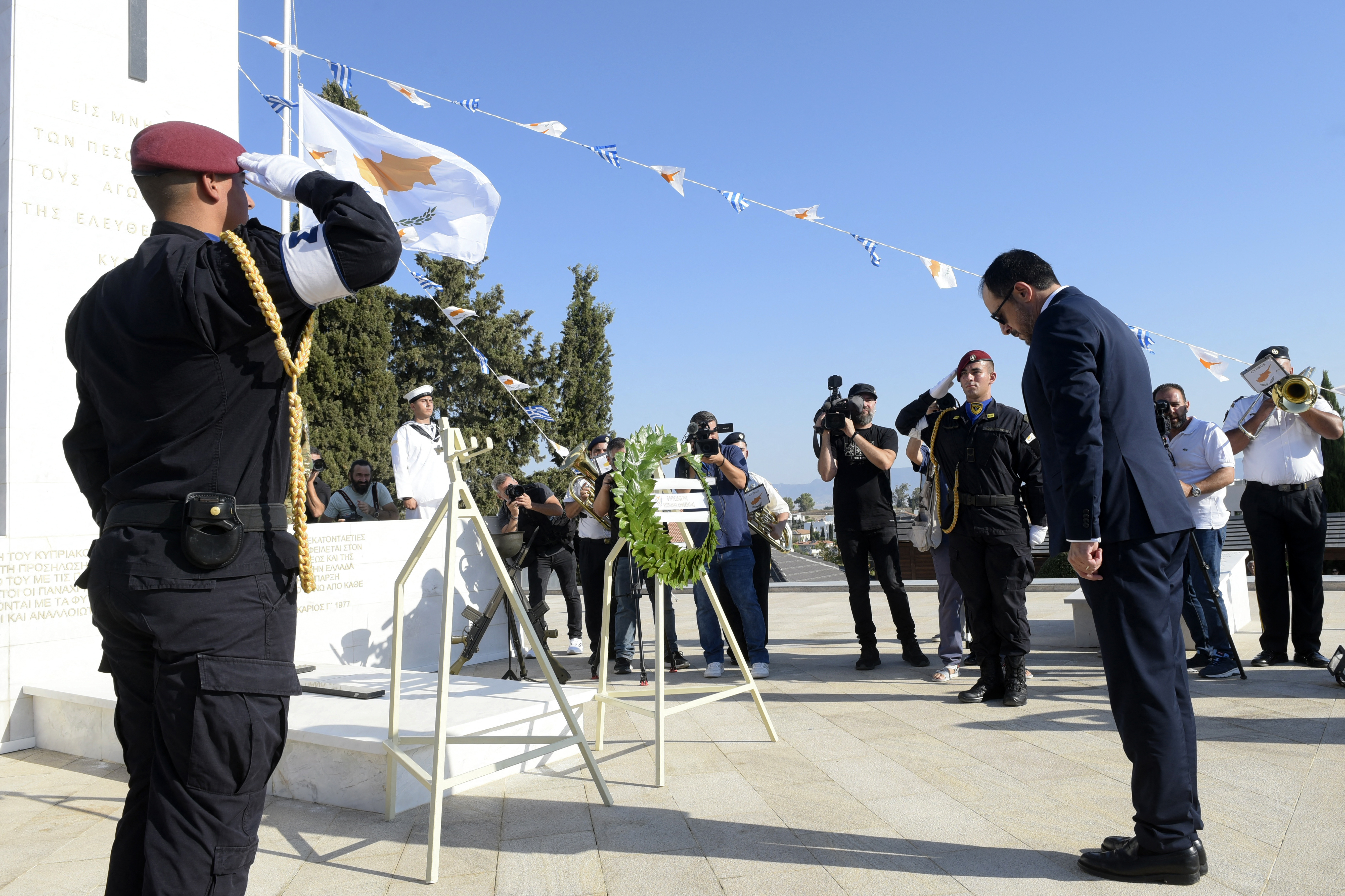 Cypriot President Nikos Christodoulides (R) bows in front of a monument erected in memory of soldiers killed in the 1974 Turkish invasion of Cyprus at the Tymvos Makedonitissas military cemetery in Nicosia on July 20, 2024. Sirens pierced the pre-dawn quiet in Cyprus on July 20 to mark 50 years since Turkish troops landed on the Mediterranean island in an invasion that has left it divided to this day. (Photo by Iakovos HATZISTAVROU / AFP)