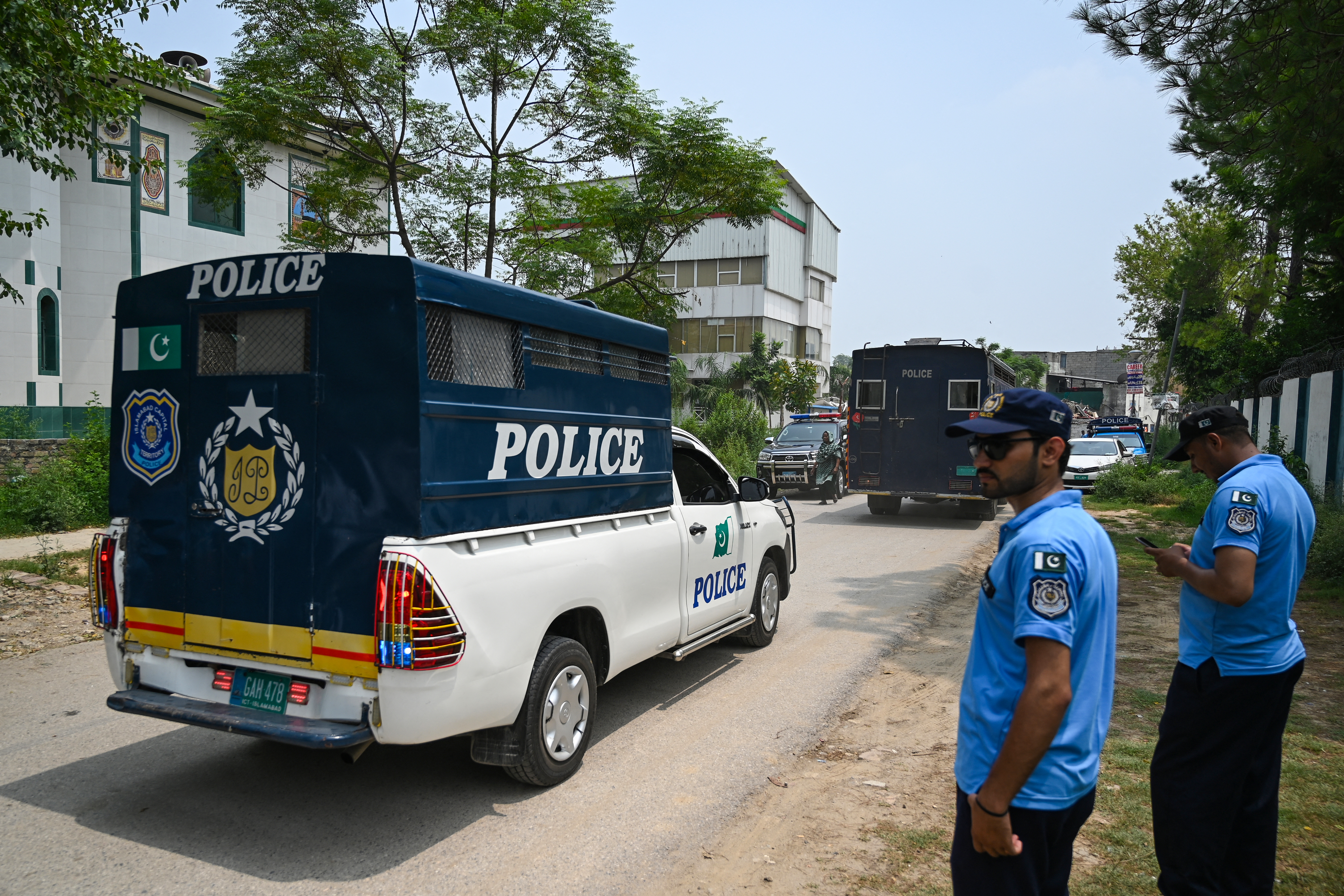 Policemen make way for prison van afer a security raid at the Pakistan Tehreek-e-Insaf (PTI) party's headquarters in Islamabad on July 22, 2024. - Pakistan police raided the headquarters of jailed former prime minister Imran Khan's party on July 22, a week after the military-backed government vowed to ban the political movement. (Photo by Aamir QURESHI / AFP)