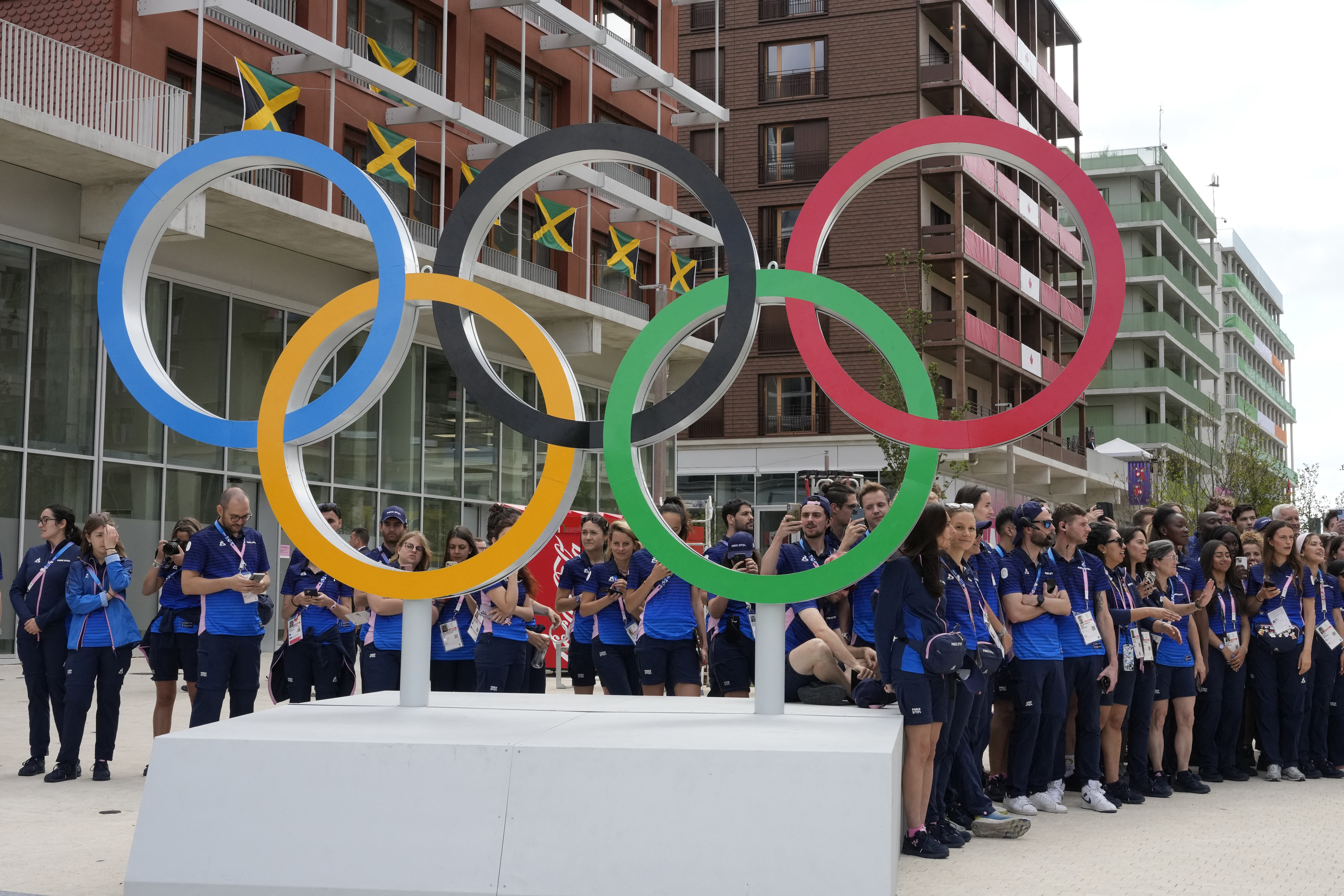 Athlete standing behind Olympic rings in Paris, France.