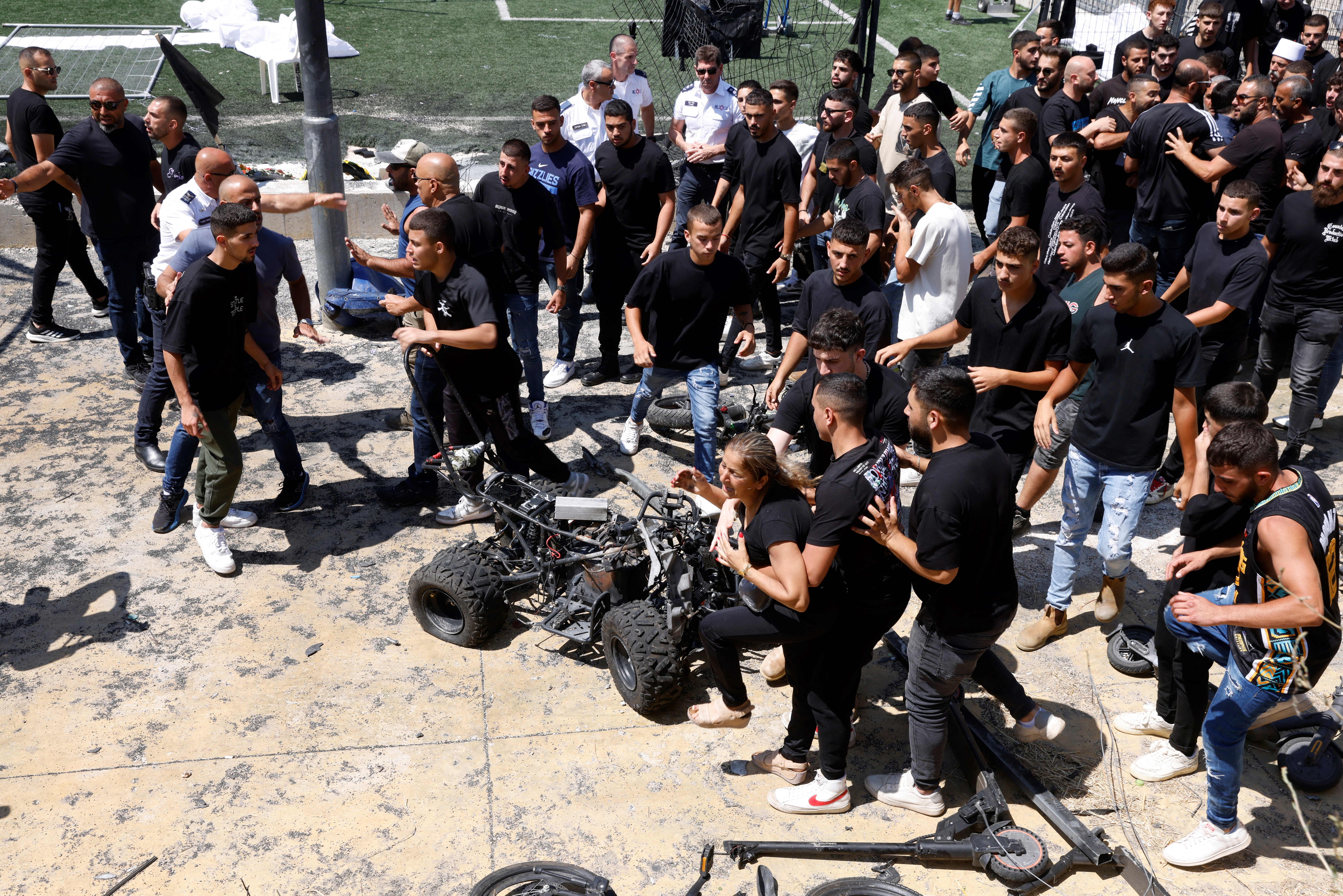 A woman is held back as she tries to retrieve a scooter as demonstrators gather during a visit by the Israeli Prime Minister two days after a rocket crashed killing 12 youngsters in the Druze village of Majdal Shams in the Israeli annexed Golan Heights, on July 29, 2024, amid ongoing cross-border clashes between Israeli troops and Hezbollah fighters. Scores of residents of Majdal Shams protested against Netanyahu's visit while he vowed Israel would deliver a "severe response" to the rocket fire that he blamed on Hezbollah, killing 12 youths aged between 10 and 16 years. The Lebanese Shiite militant group has denied responsibility for the strike. (Photo by Jalaa MAREY / AFP) RELATED CONTENT