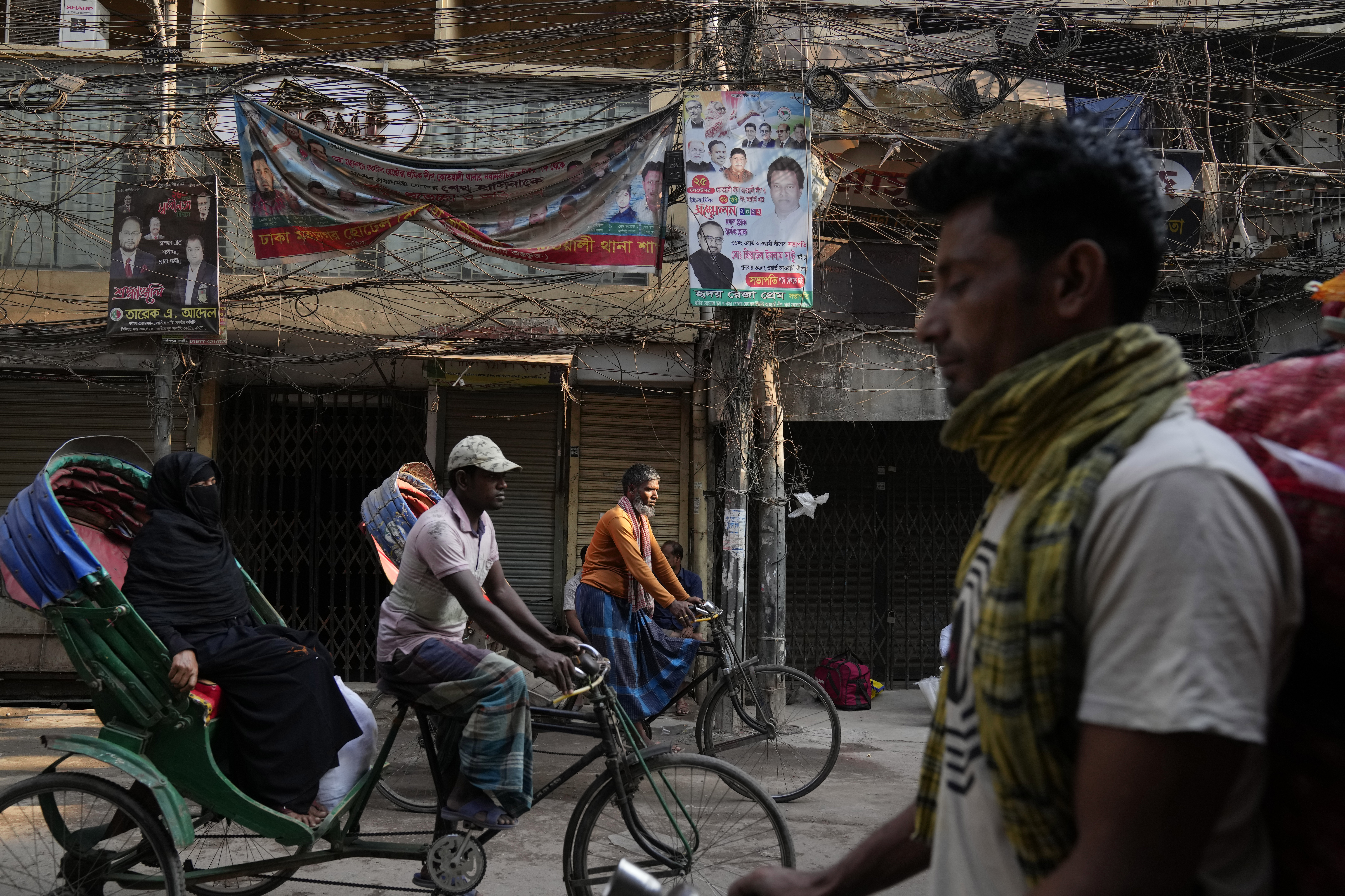 A cycle rickshaw puller pedals with a passenger in the old quarters of Dhaka, Bangladesh, Monday, March 13, 2023. (AP Photo/Aijaz Rahi)