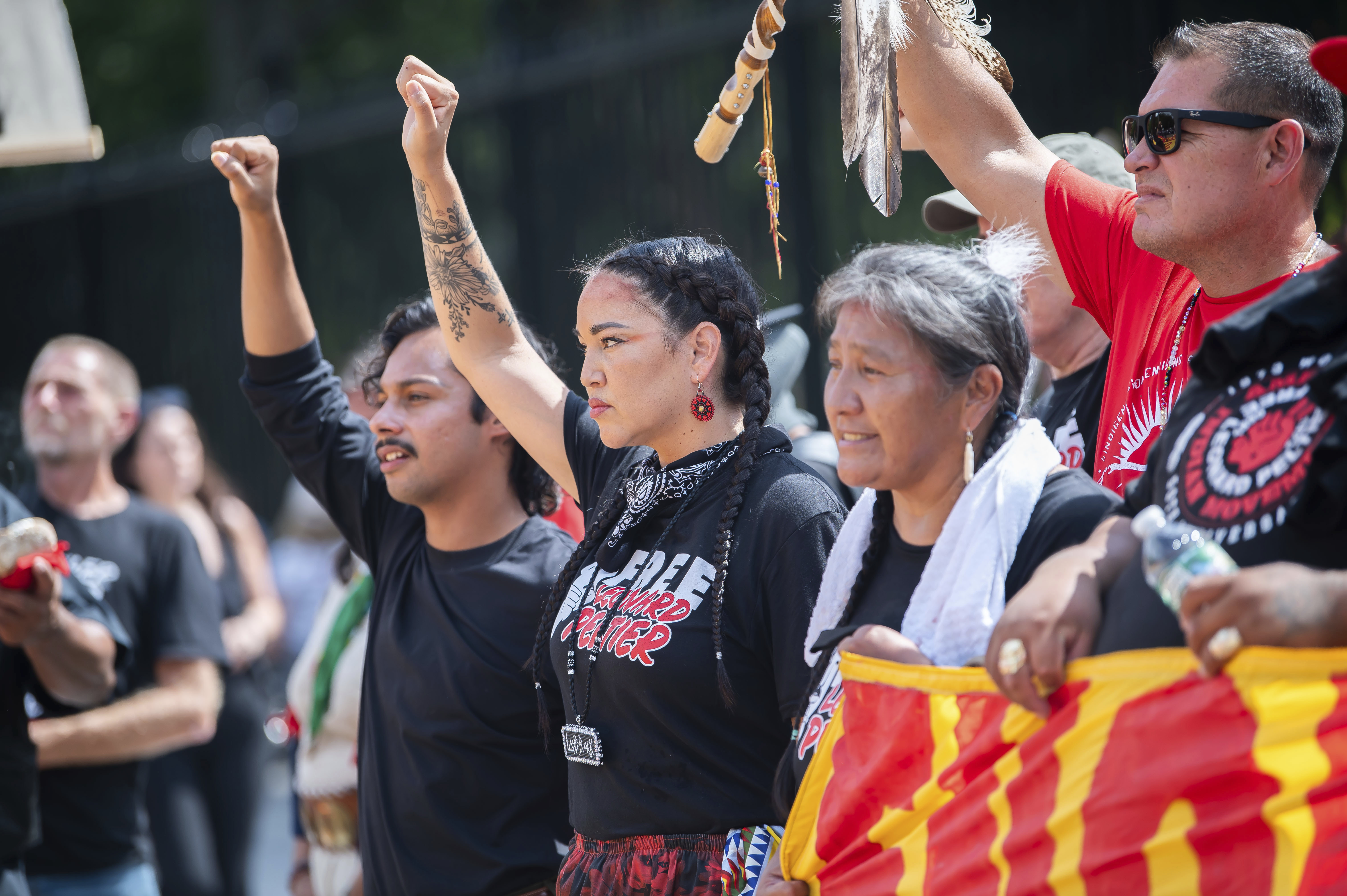 Indigenous activists raise a fist to show solidarity at an outdoor event to call for Leonard Peltier's release.