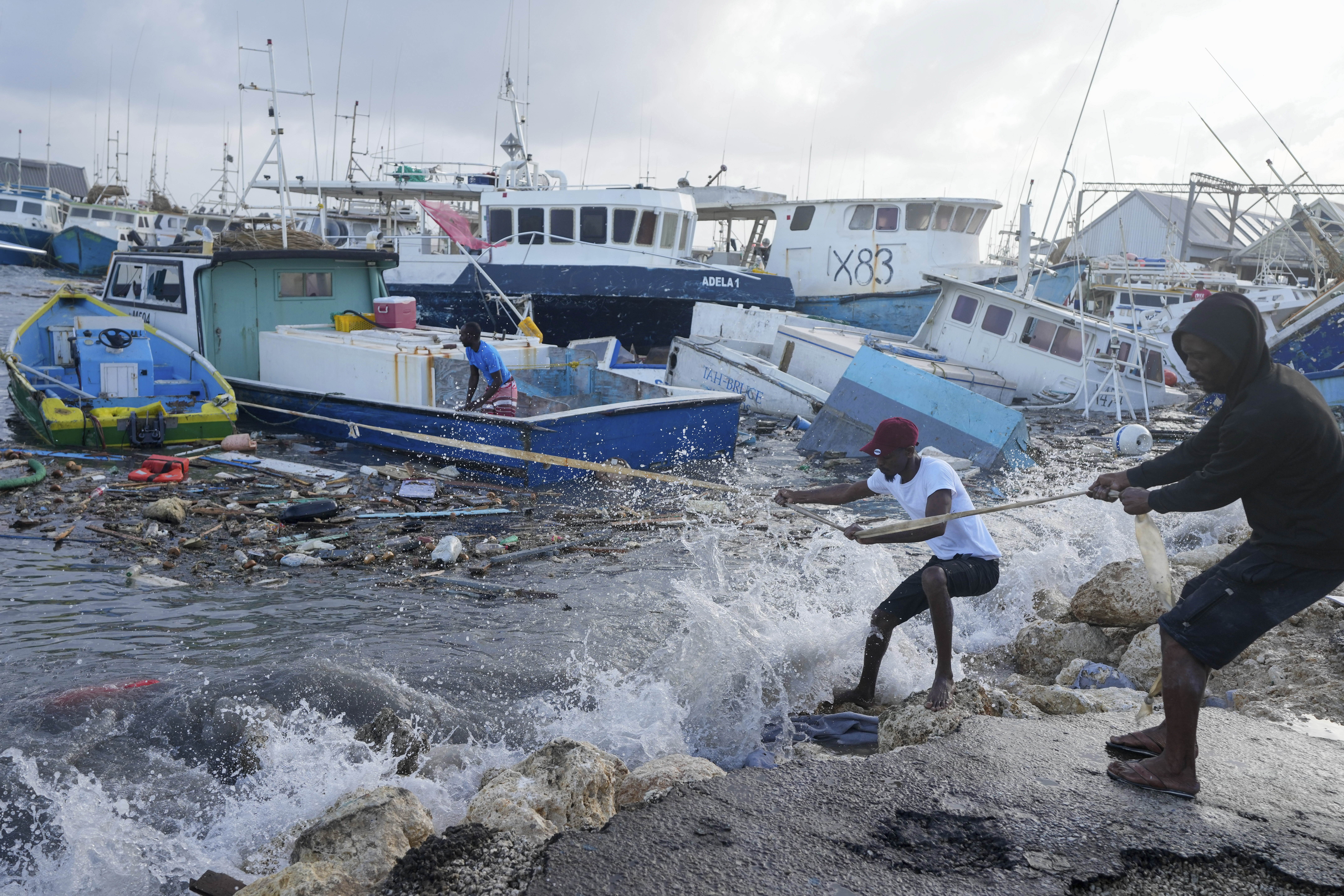 Tow men pulling a boat towards the shore amid heavy seas caused by Hurricane Beryl