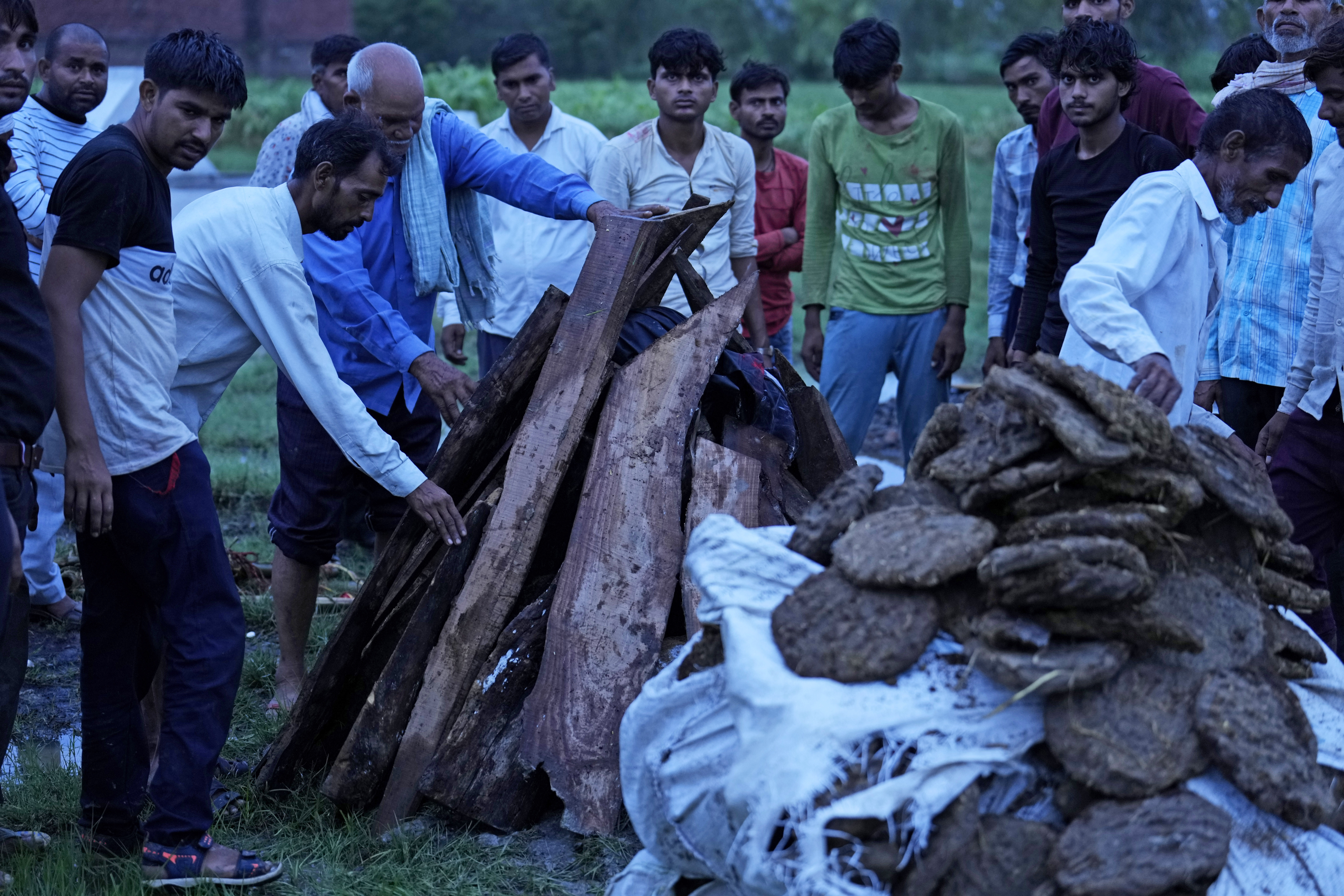 Ajay Kumar, left, stands near the funeral pyre of his mother Savitri Devi
