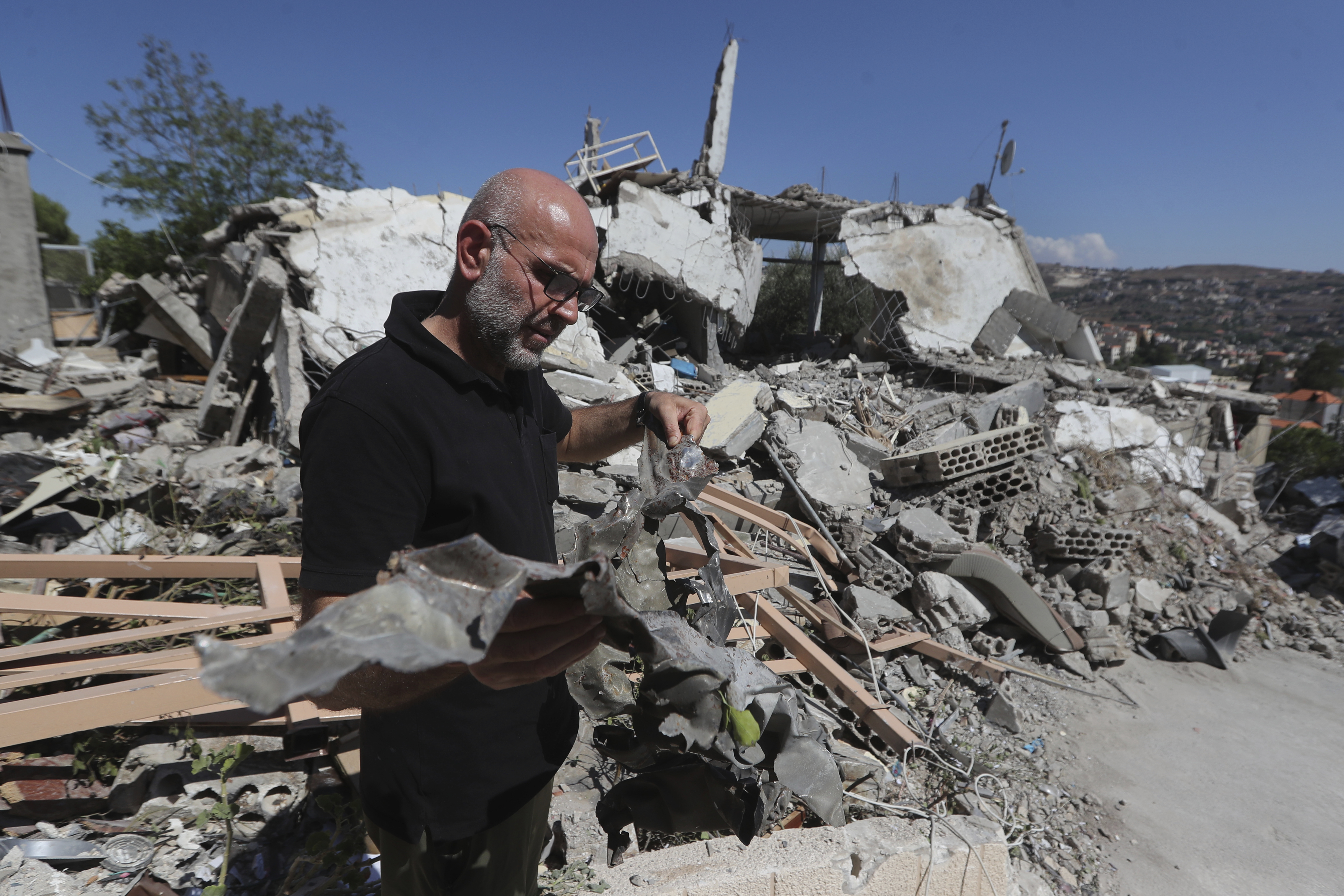 A man shows the remain of an Israeli warplane missile that hit a house and killed a Hezbollah fighter with two of his civilian family members, in Bint Jbeil town, south Lebanon, Tuesday, July 16, 2024.