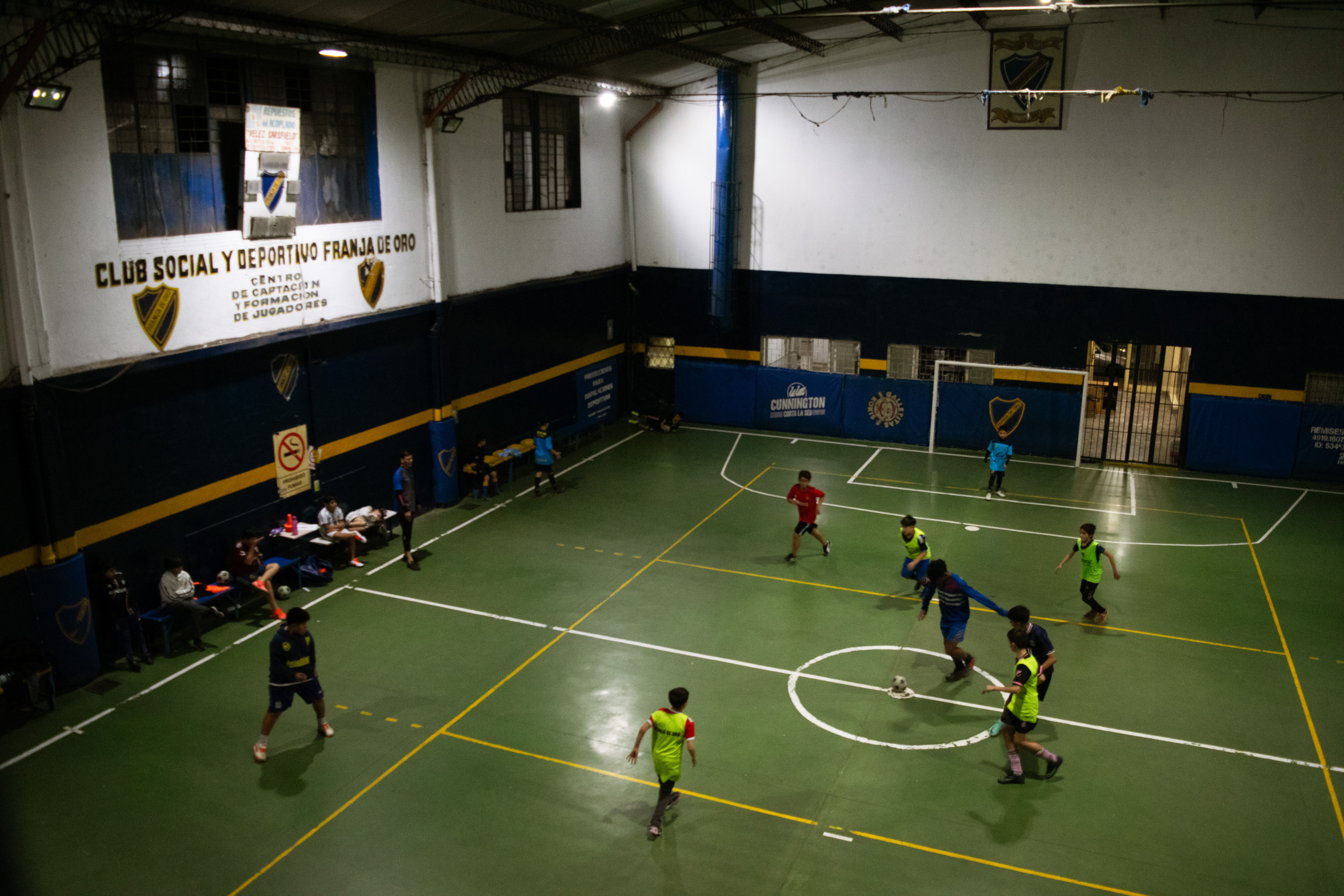 An aerial view of an indoor sports field, where children play soccer.