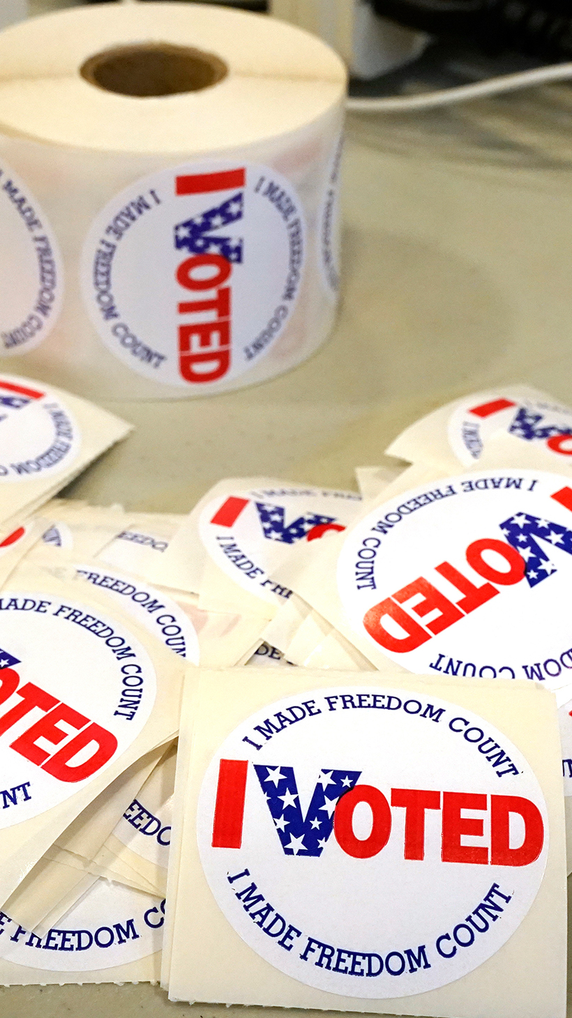 Round stickers sit on a table. They read: "I voted. I made freedom count."