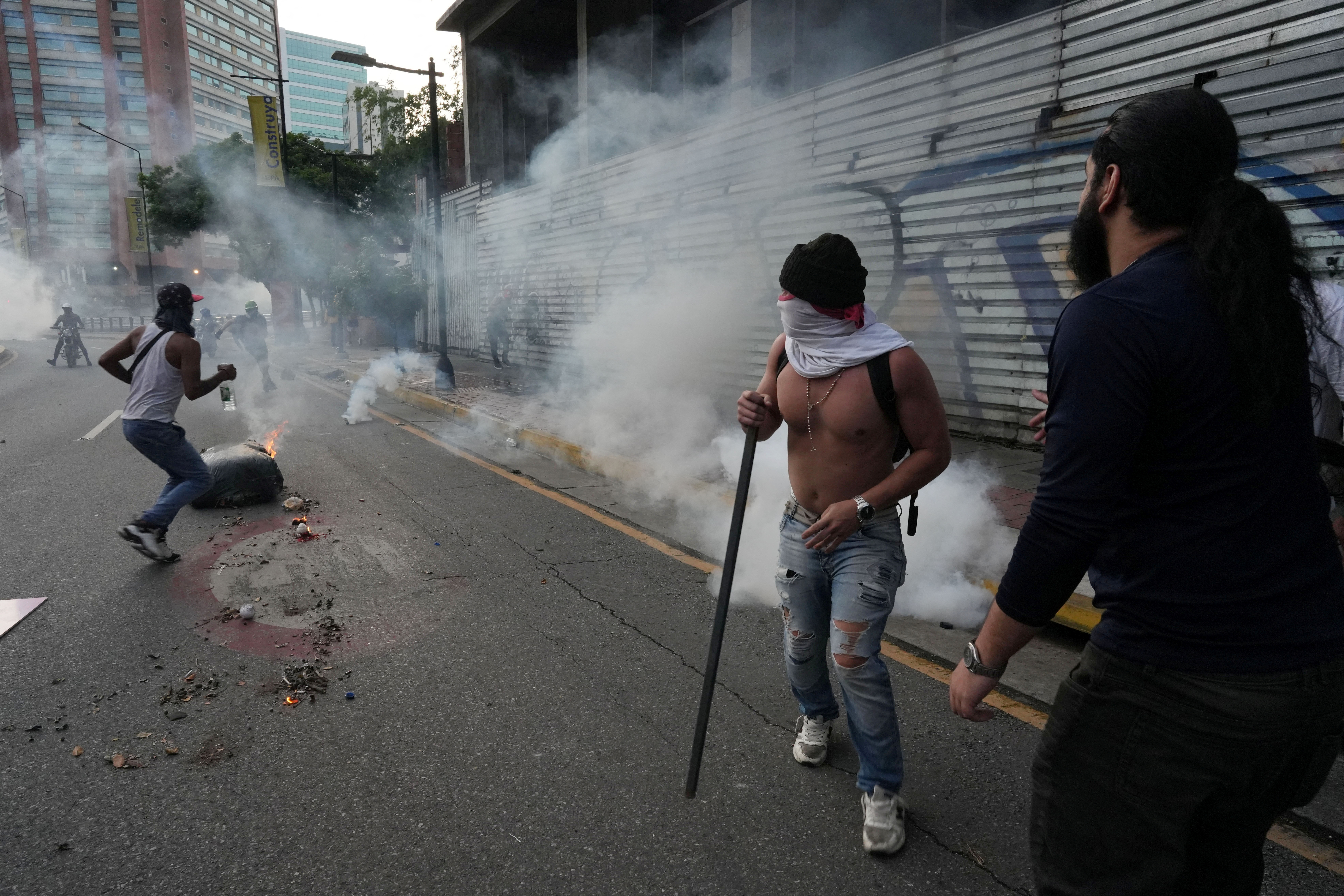Protesters take cover from tear gas as Venezuelan opposition supporters protest in the capital Caracas [Alexandre Meneghini/Reuters]