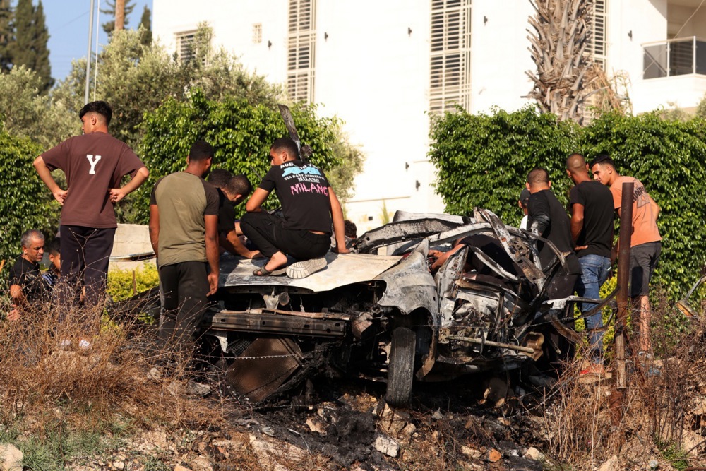 epa11520977 People inspect a car which was destroyed after an Israeli airstrike in Zeta village, north of Tulkarem city in the West Bank, 03 August 2024. At least four Palestinians inside the car were killed, according to the Palestinian Health Ministry. More than 39,000 Palestinians and over 1,400 Israelis have been killed, according to the Palestinian Health Ministry and the Israel Defense Forces (IDF), since Hamas militants launched an attack against Israel from the Gaza Strip on 07 October 2023, and the Israeli operations in Gaza and the West Bank which followed it. EPA-EFE/ALAA BADARNEH