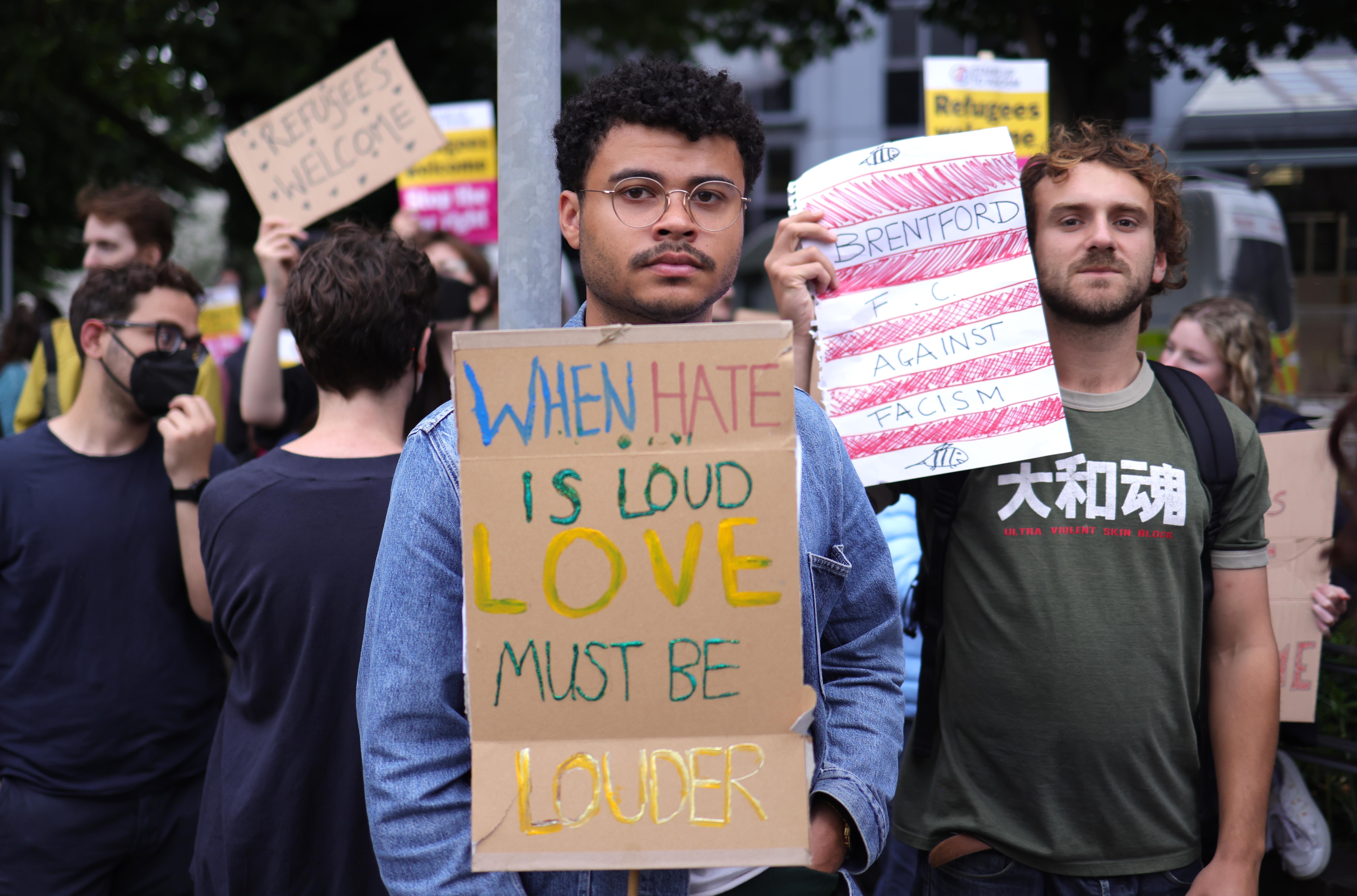 man holds banner saying 'when hate is loud love must be louder'