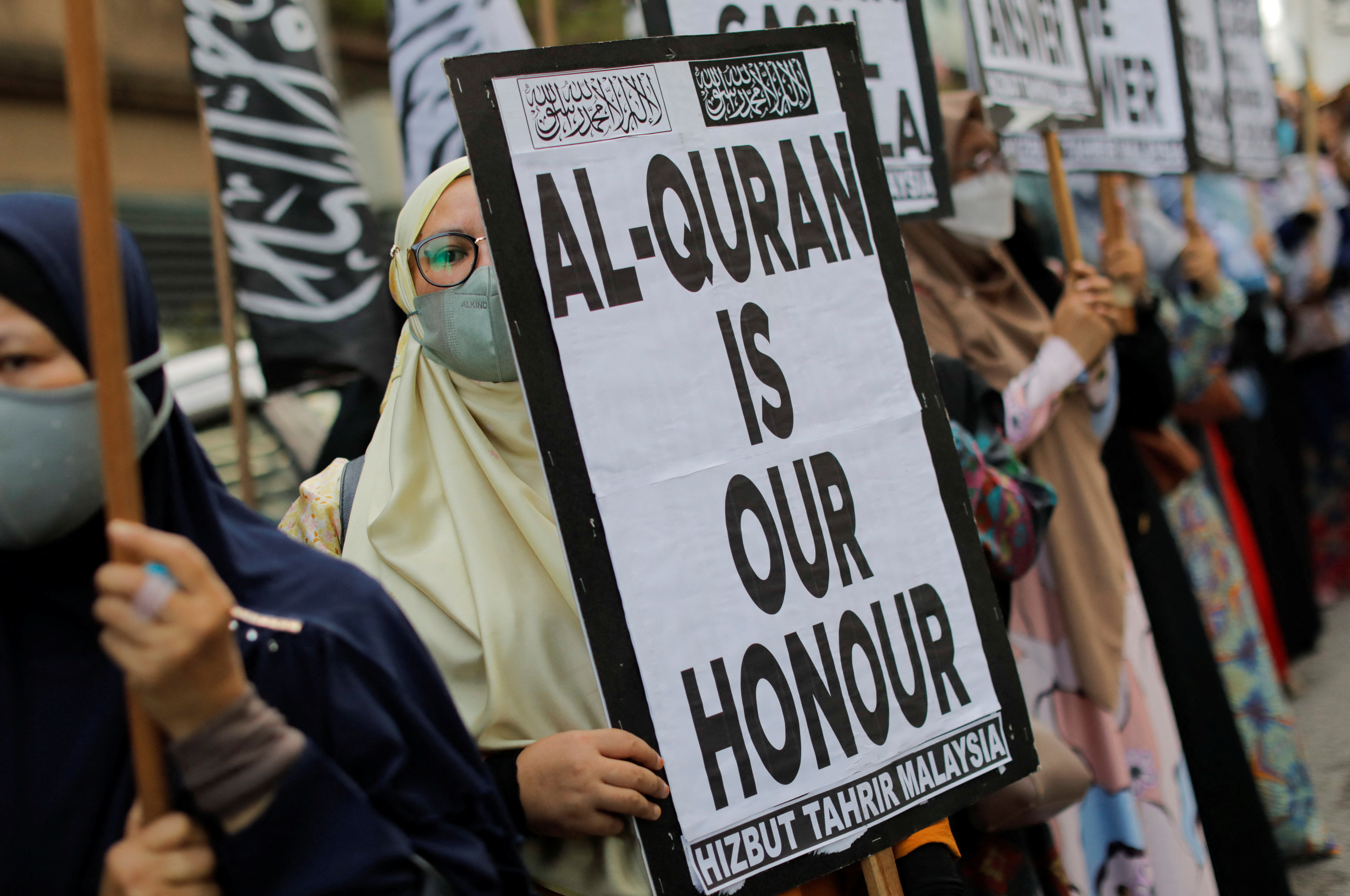 A woman holds a placard that reads " Al-Quran is our honour" during a protest in front of the Swedish embassy after Rasmus Paludan, leader of Danish far-right political party Hard Line burned a copy of the Koran